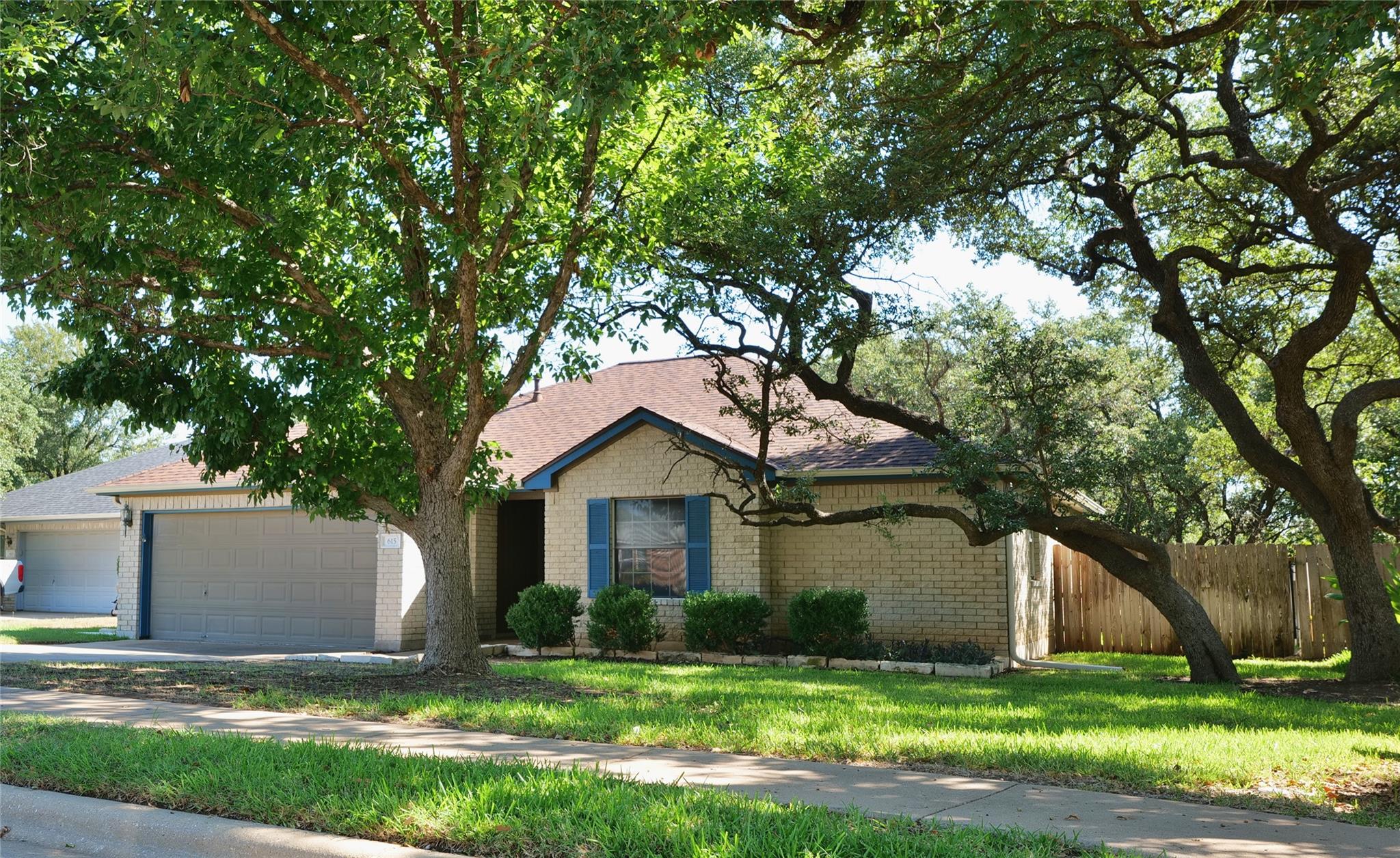 Mature shade trees frame a brick exterior with an