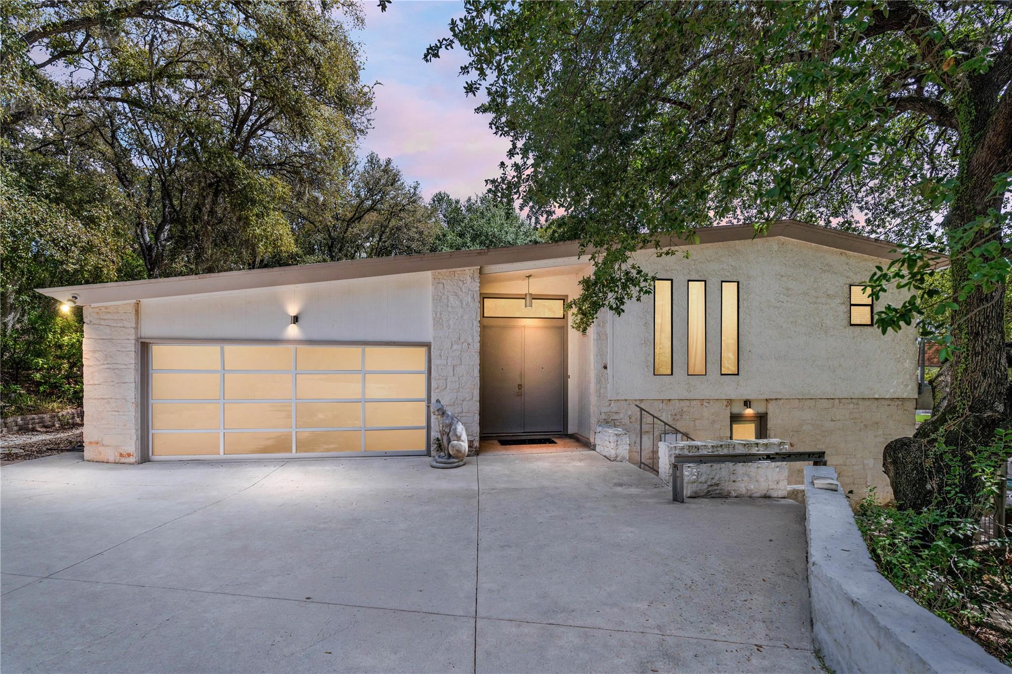 Mature oak trees frame a modern multi-level facad