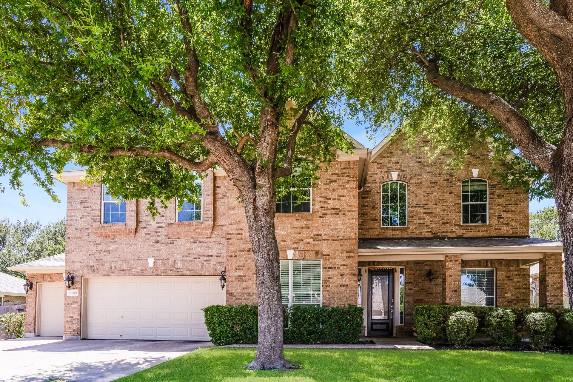 A classic brick exterior stands framed by mature 