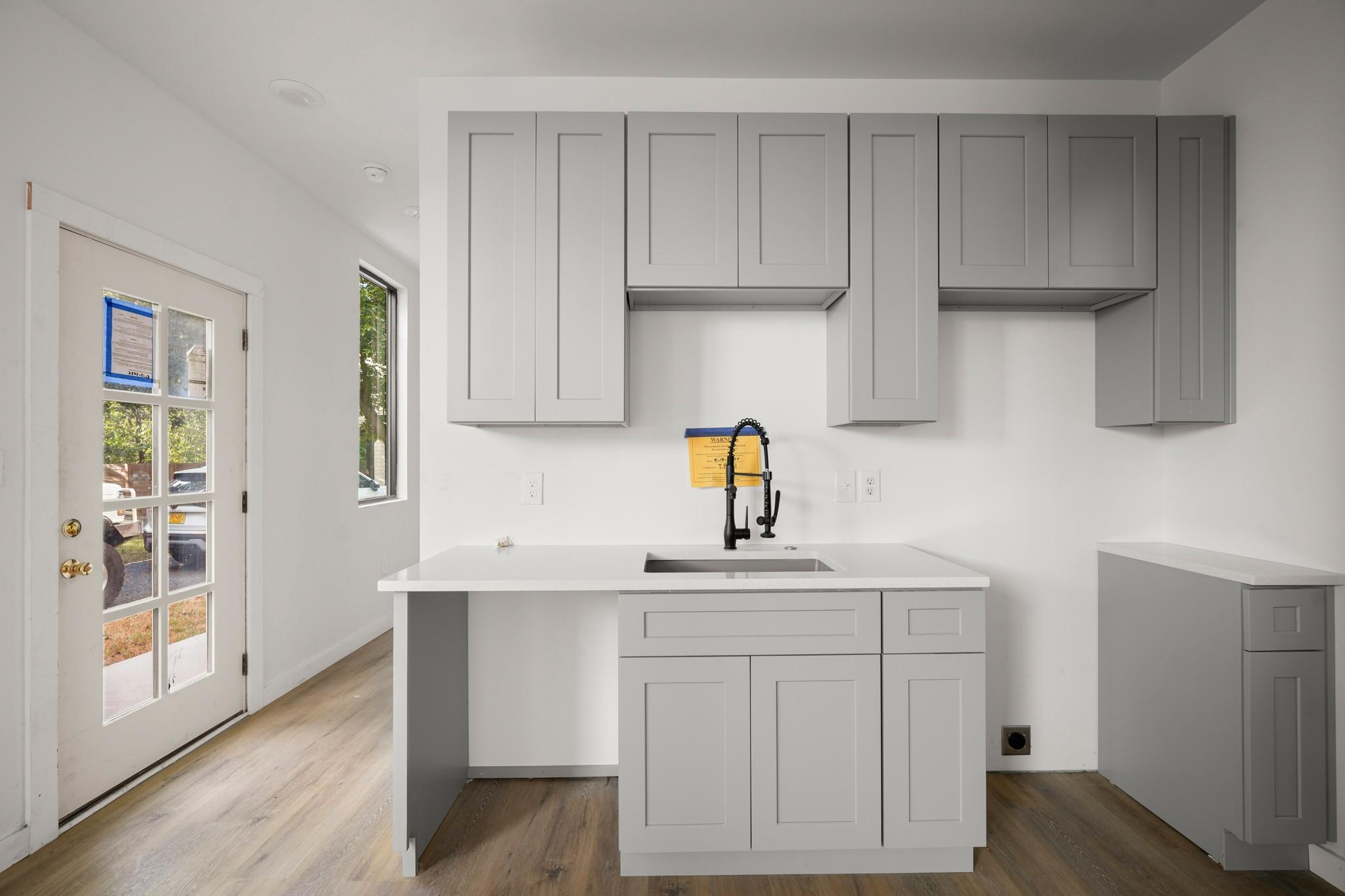 A modern kitchenette area features shaker cabinet
