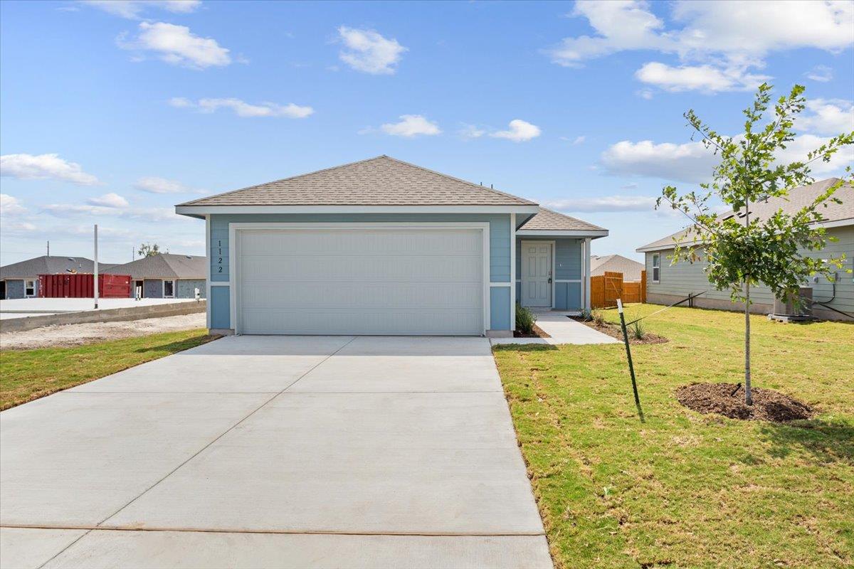 A wide concrete driveway leads past a grassy lawn