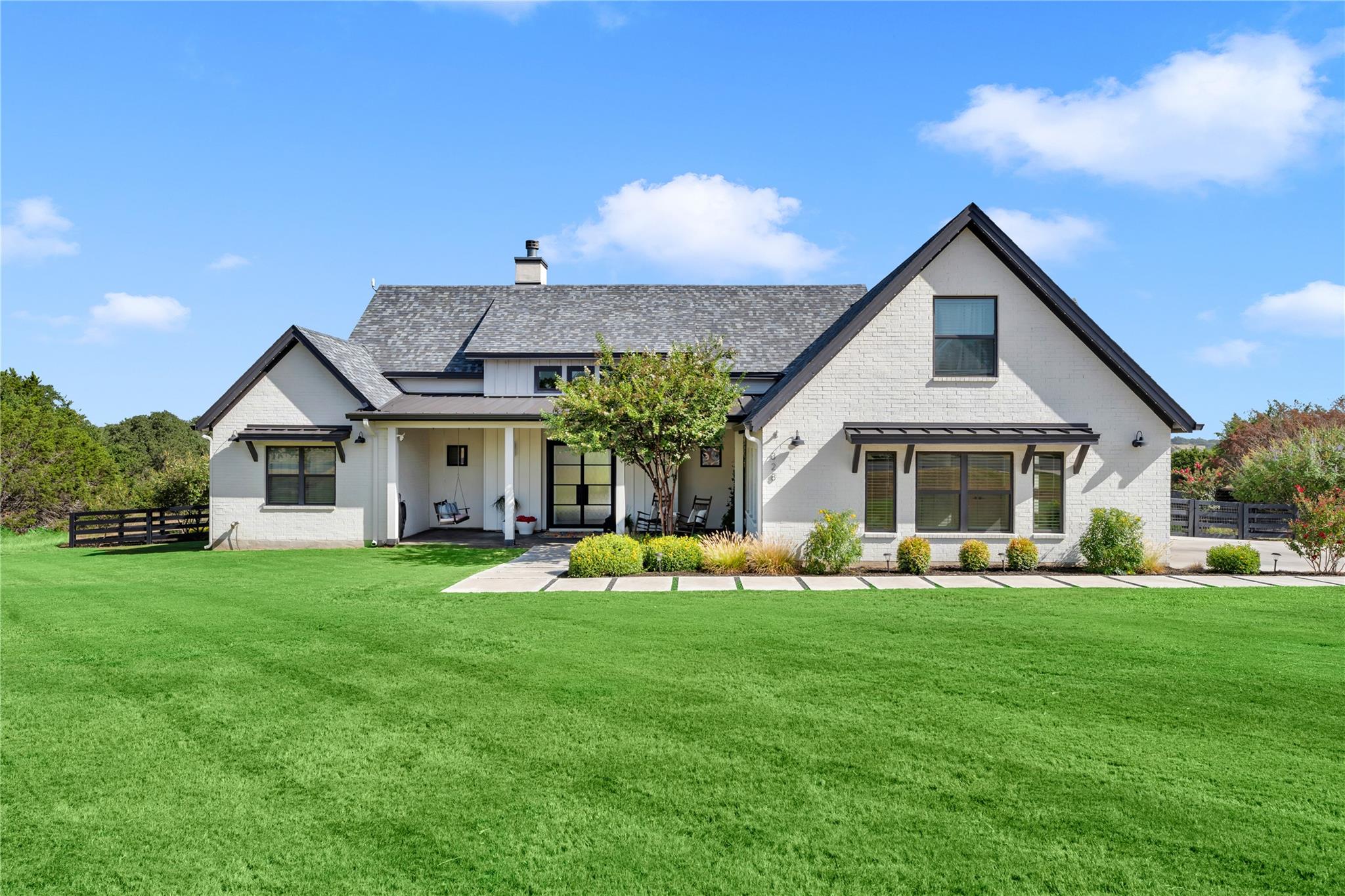 An immaculate modern farmhouse facade rises above