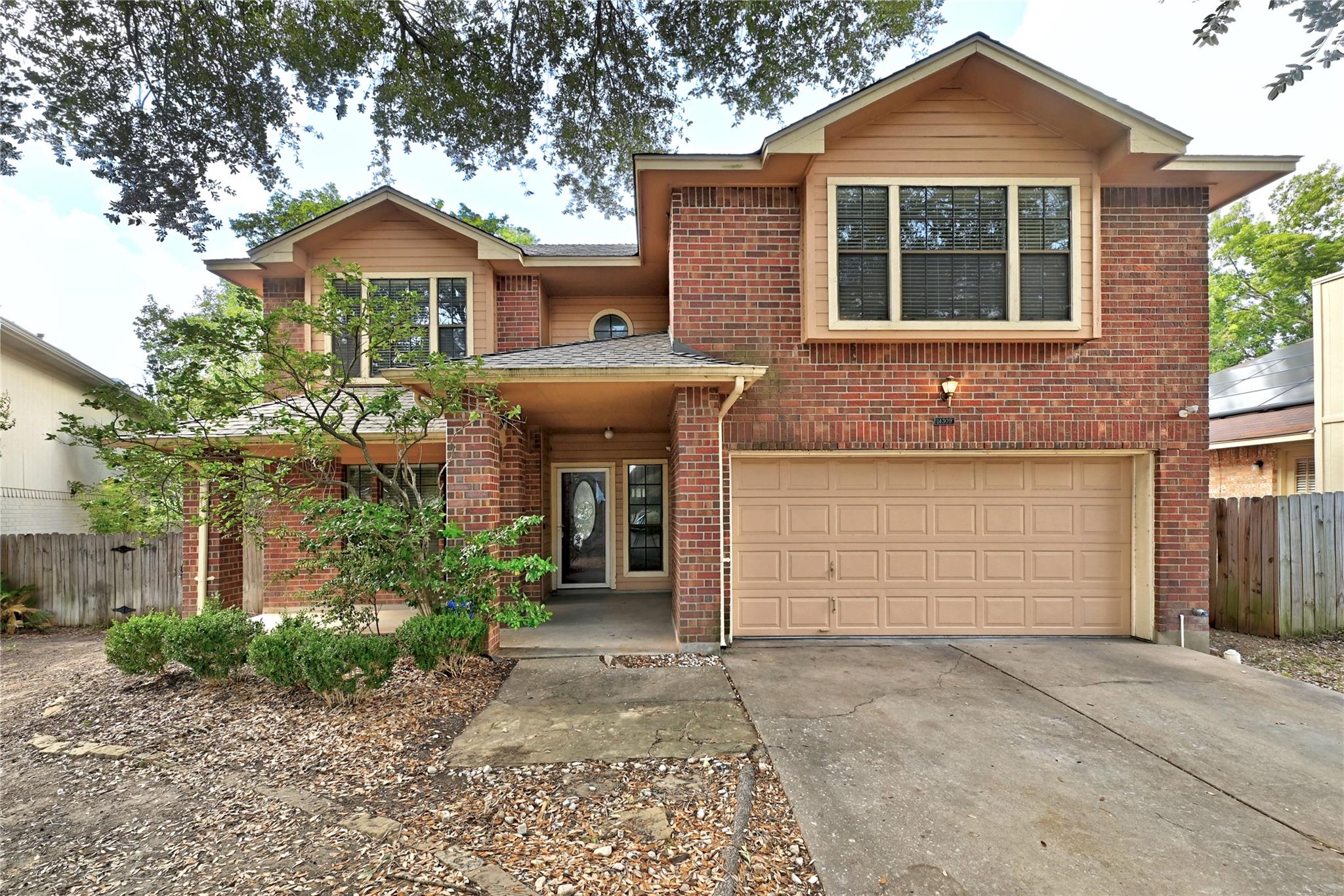 Mature trees shade a classic brick two-story faca
