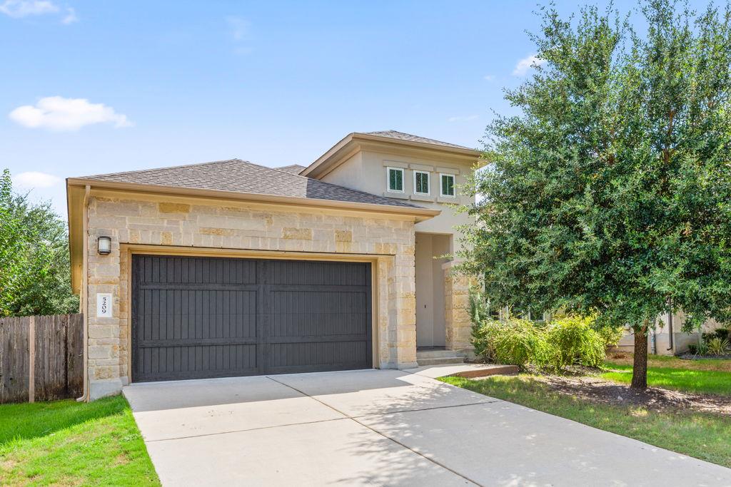 Natural stone masonry and a dark garage door crea