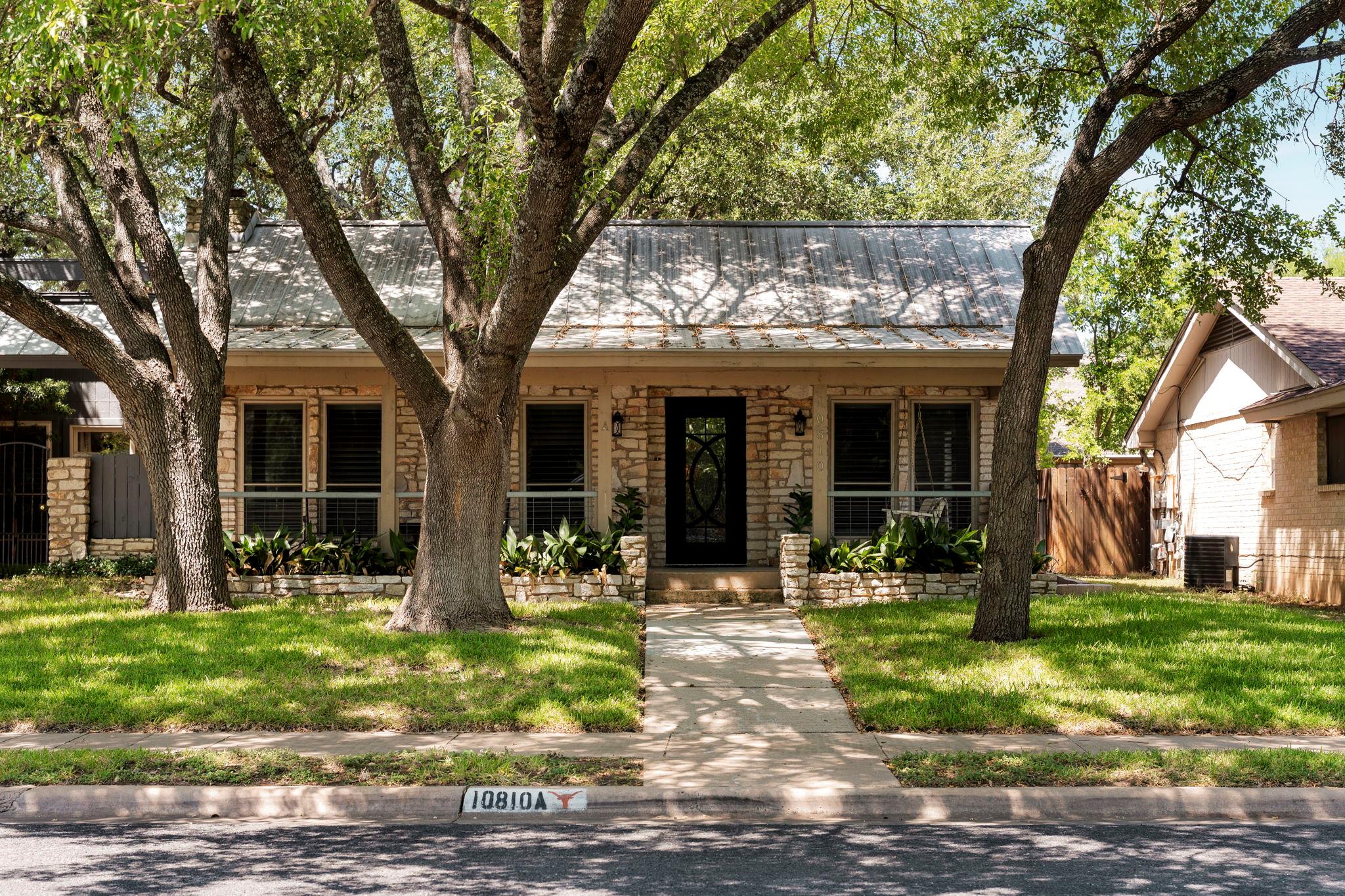 Mature trees shade a classic stone-accented facad