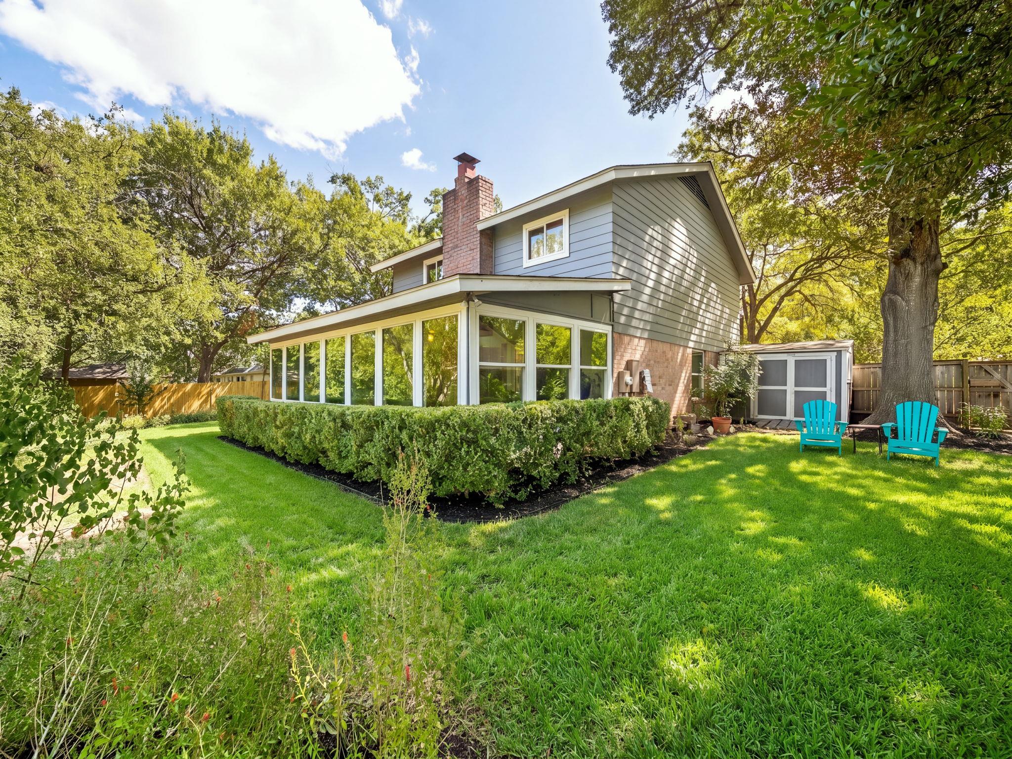 Mature trees frame a spacious lawn surrounding th