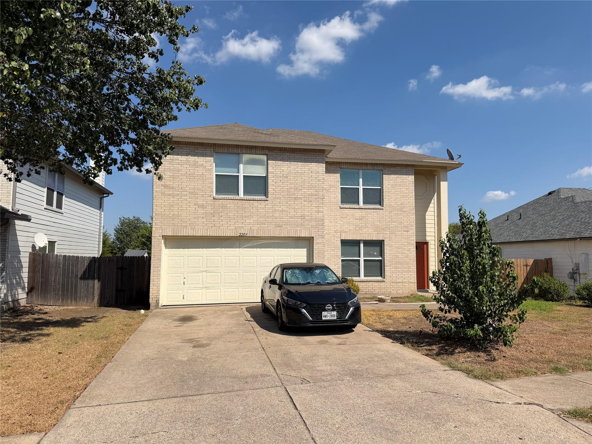 A classic brick exterior and concrete driveway fr