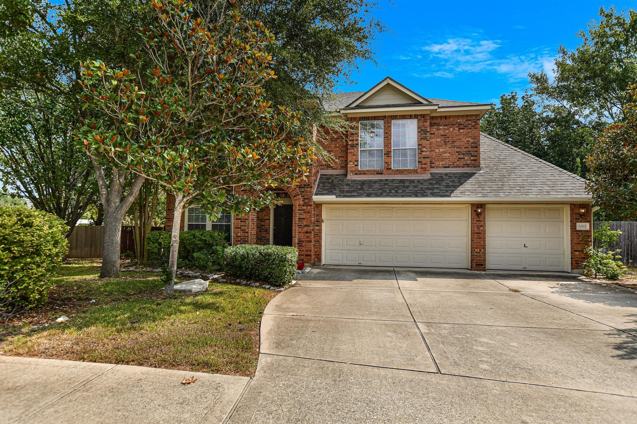 Mature trees shade the classic brick exterior and
