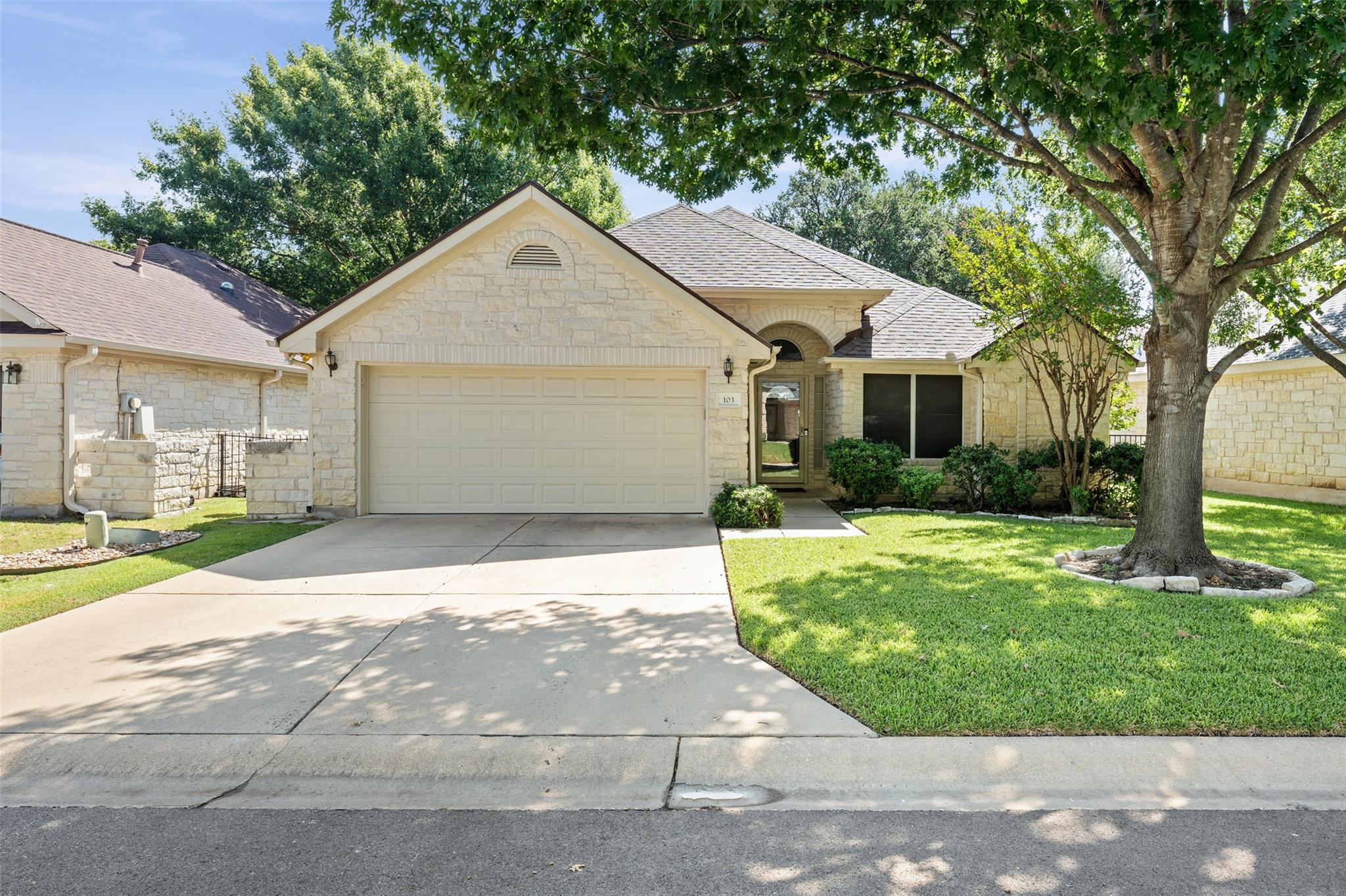Mature trees shade a welcoming stone exterior and