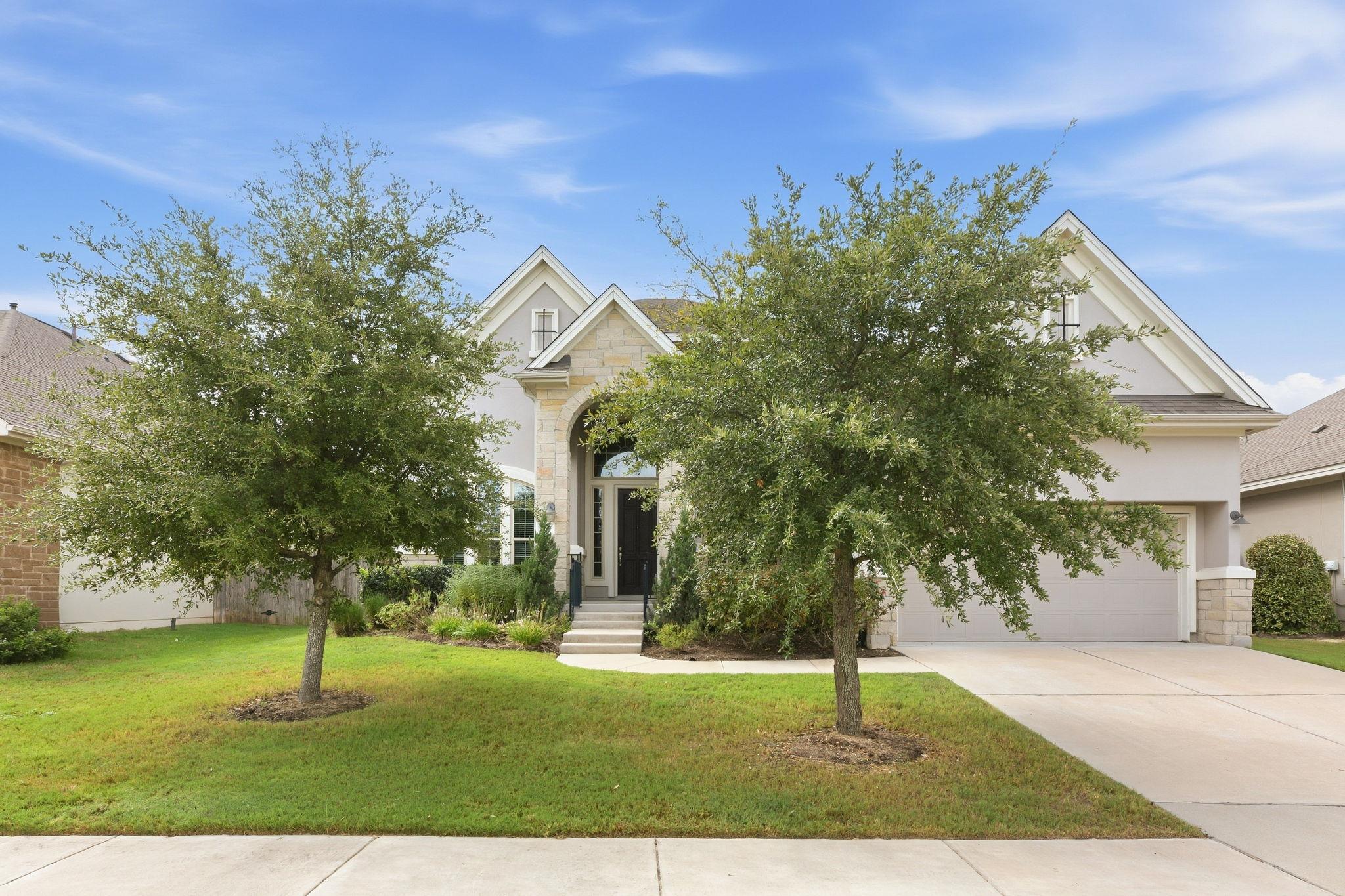 Mature trees frame the stone-accented facade and 