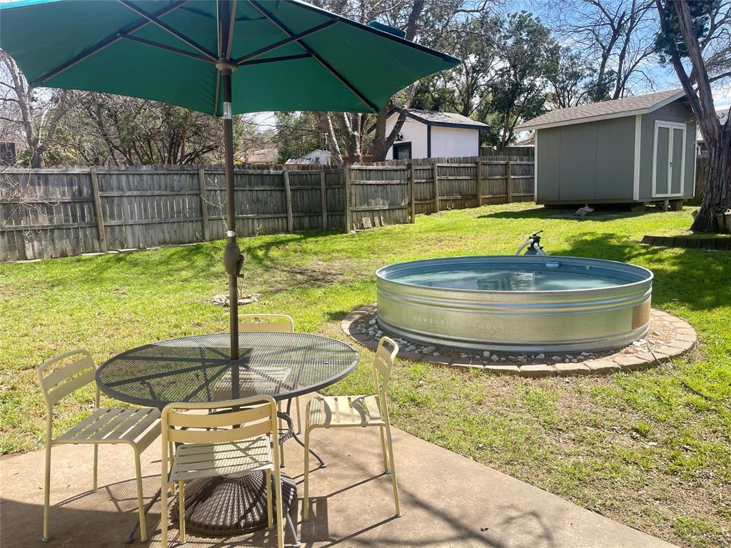 A spacious grassy yard features a stock tank pool