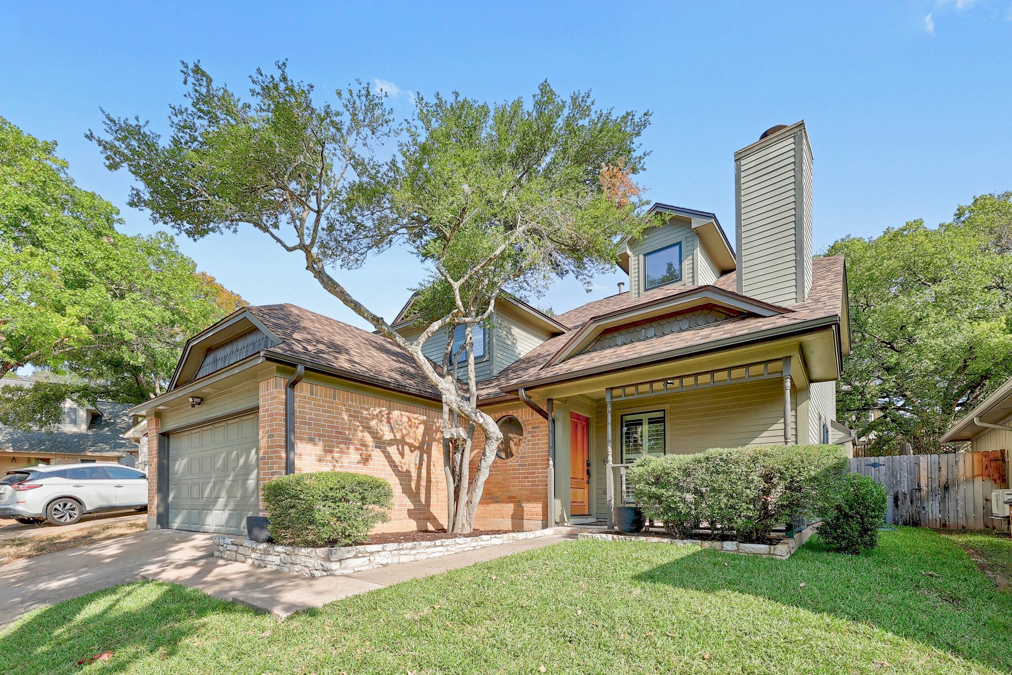 Mature trees shade the brick and siding exterior 