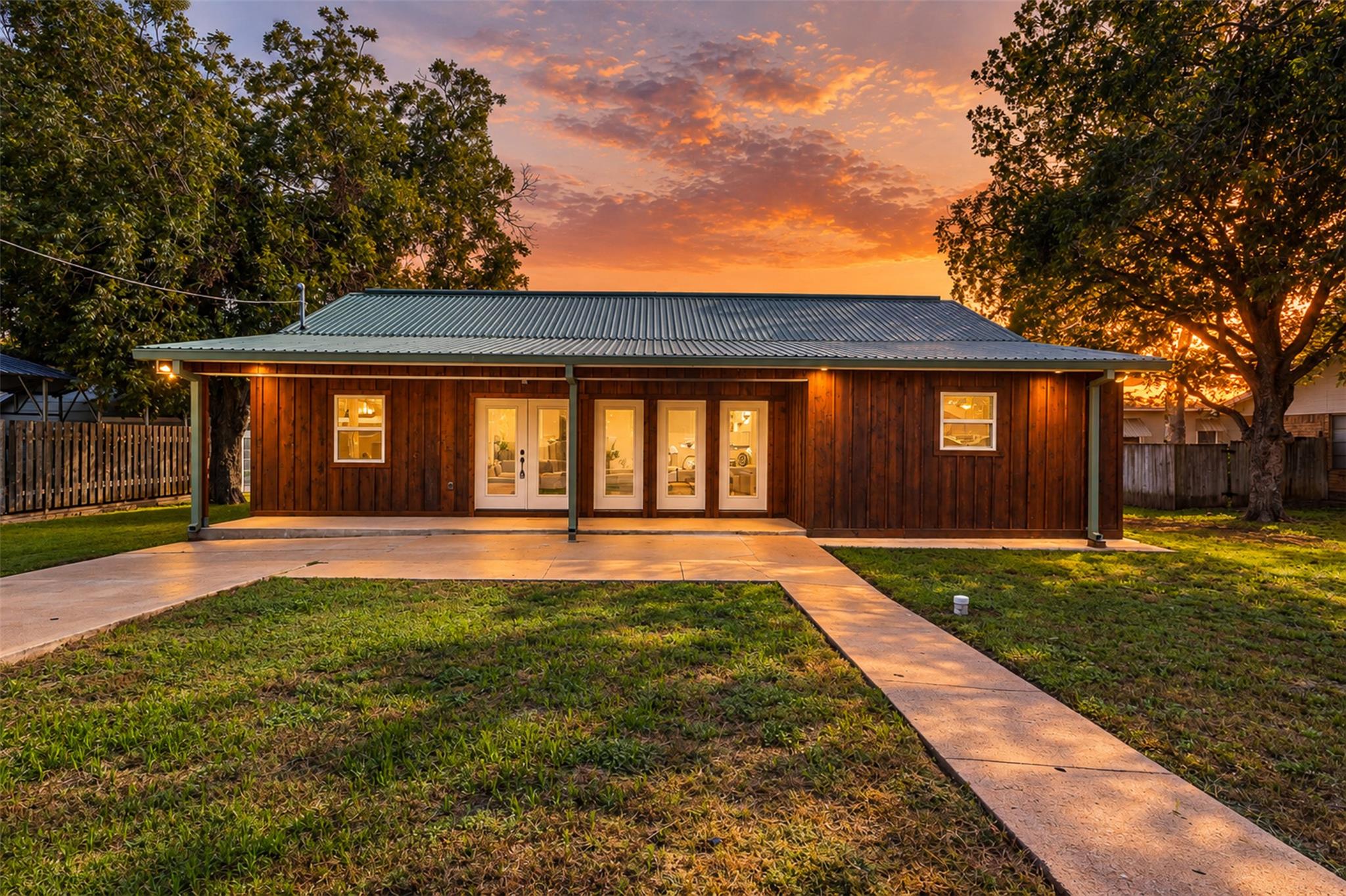 Warm exterior lights illuminate the wood-sided fa