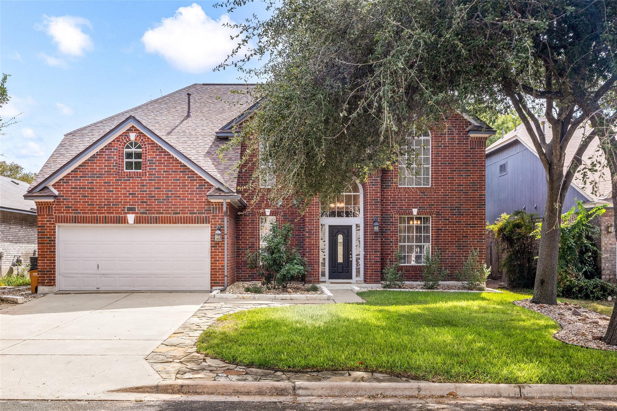 Mature trees shade a classic brick exterior accen
