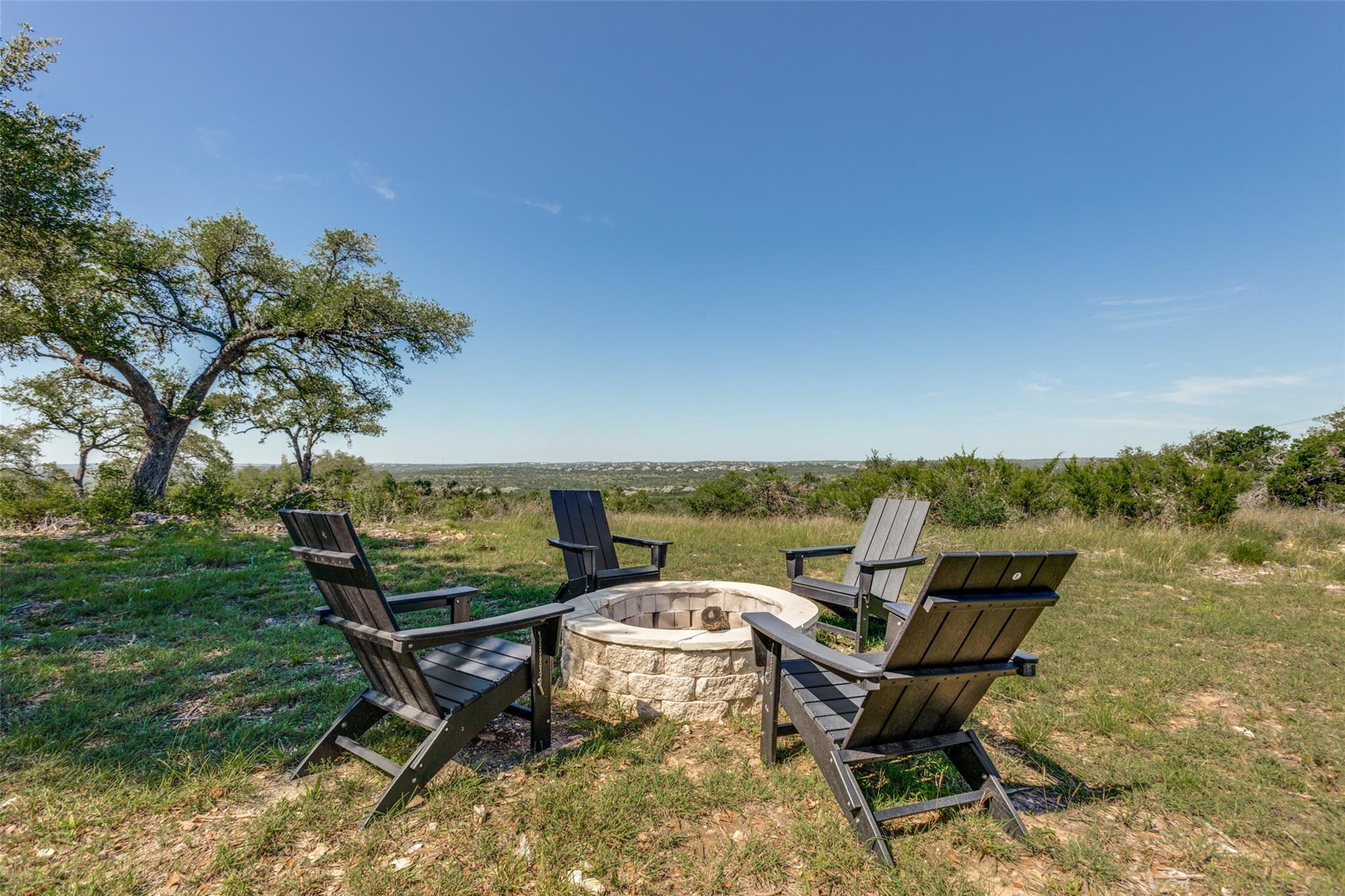 A stone fire pit overlooks expansive, tree-dotted