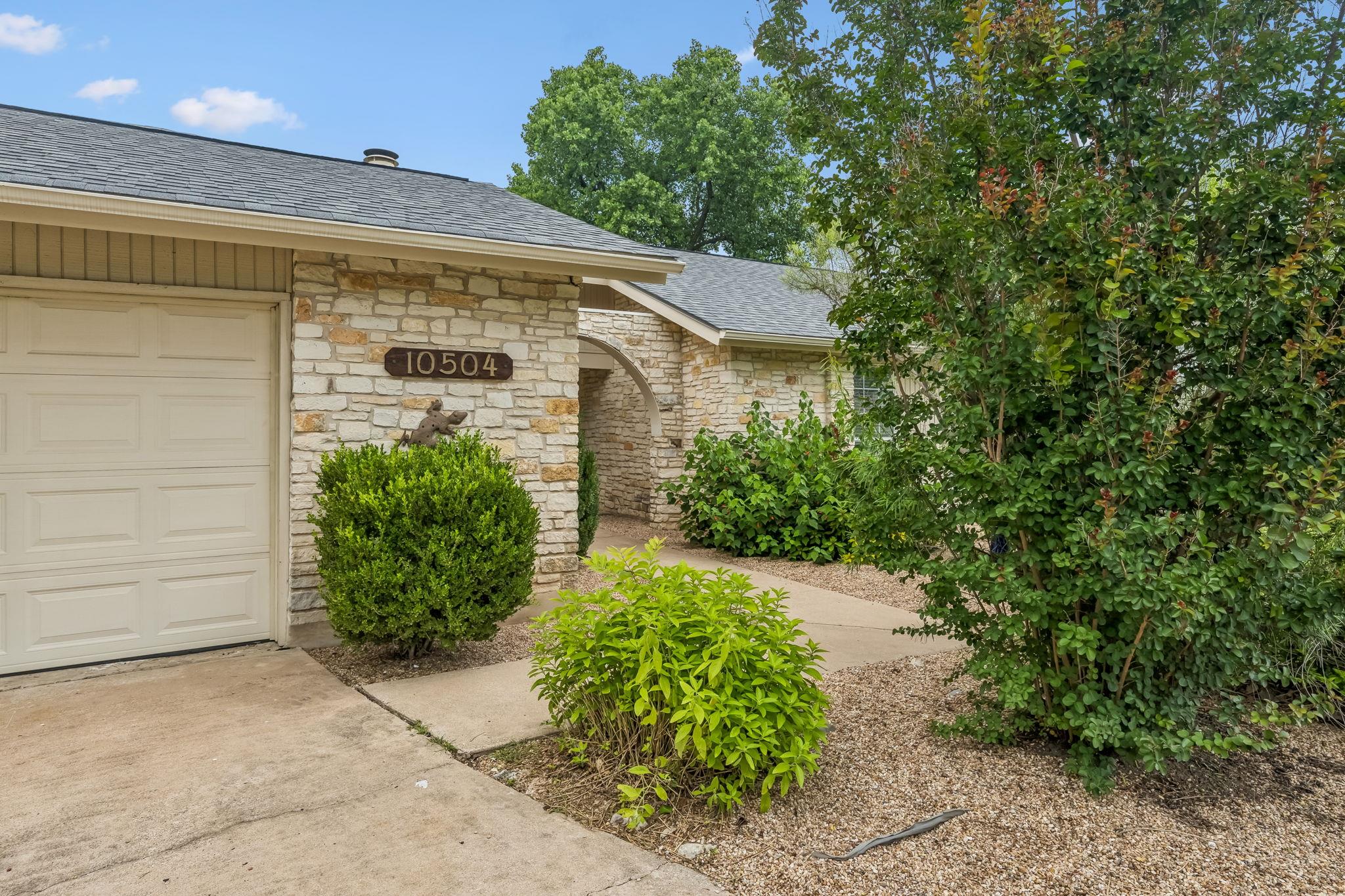 A stone exterior meets a concrete driveway under 