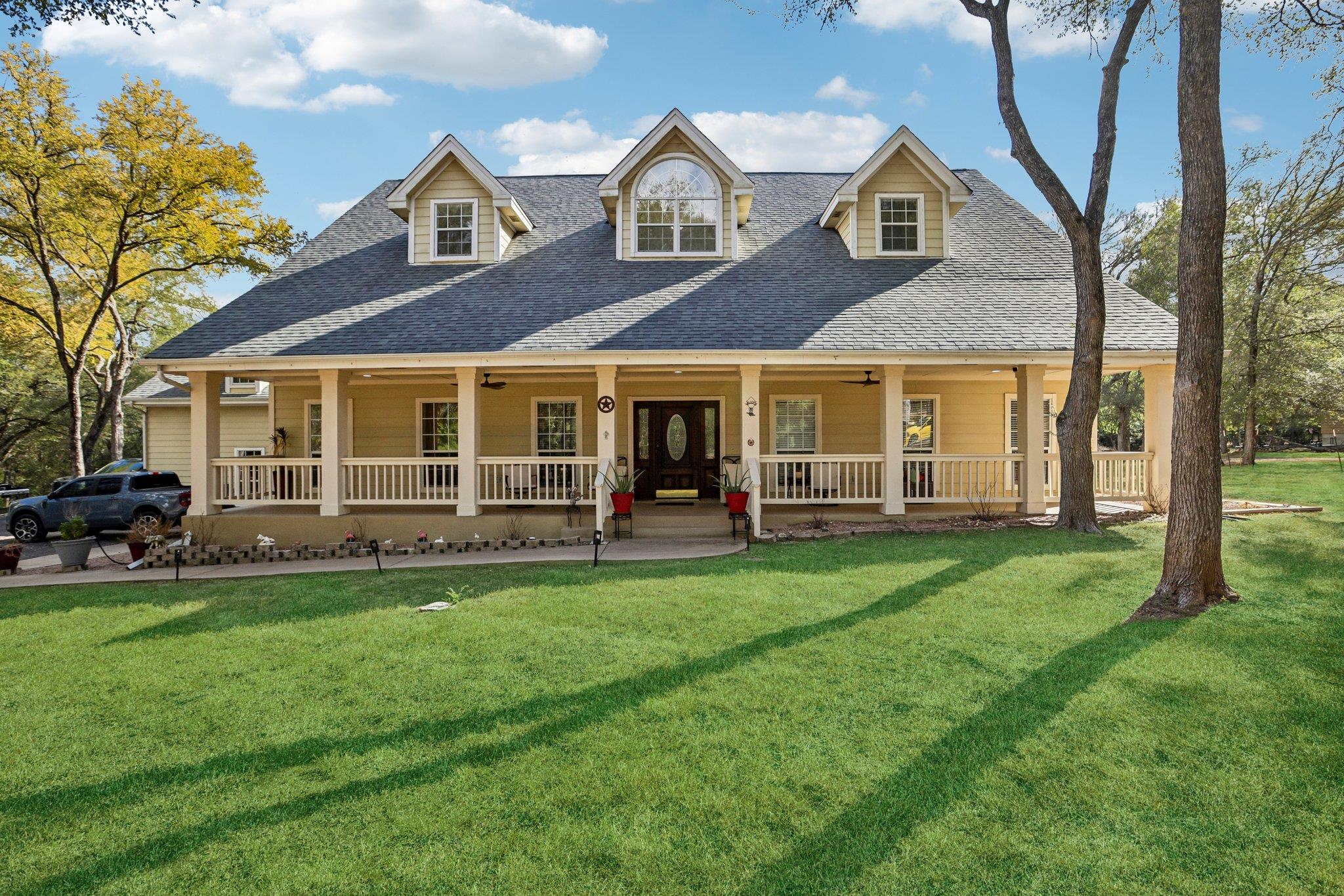 Mature trees shade a sprawling front lawn leading