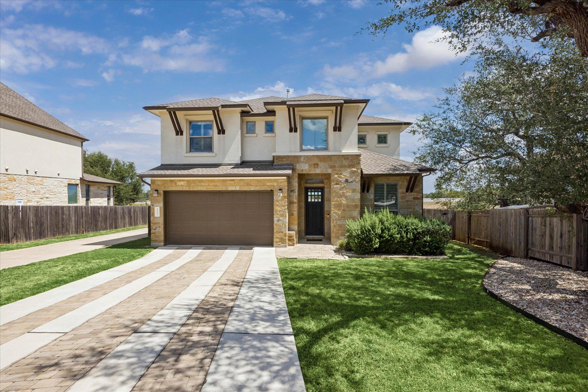 A stone and stucco exterior pairs with a paved dr
