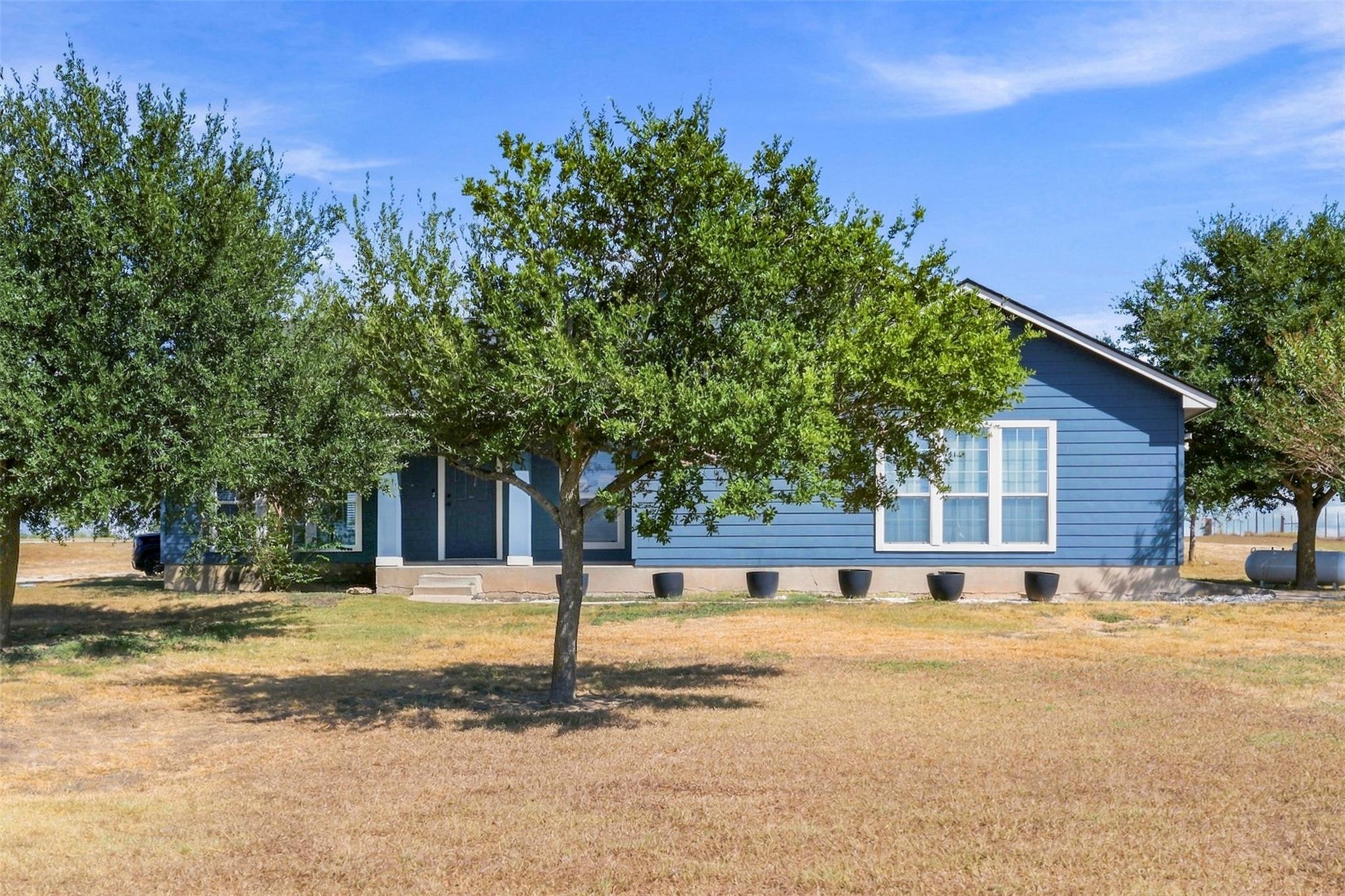 Mature trees frame the charming siding facade of 