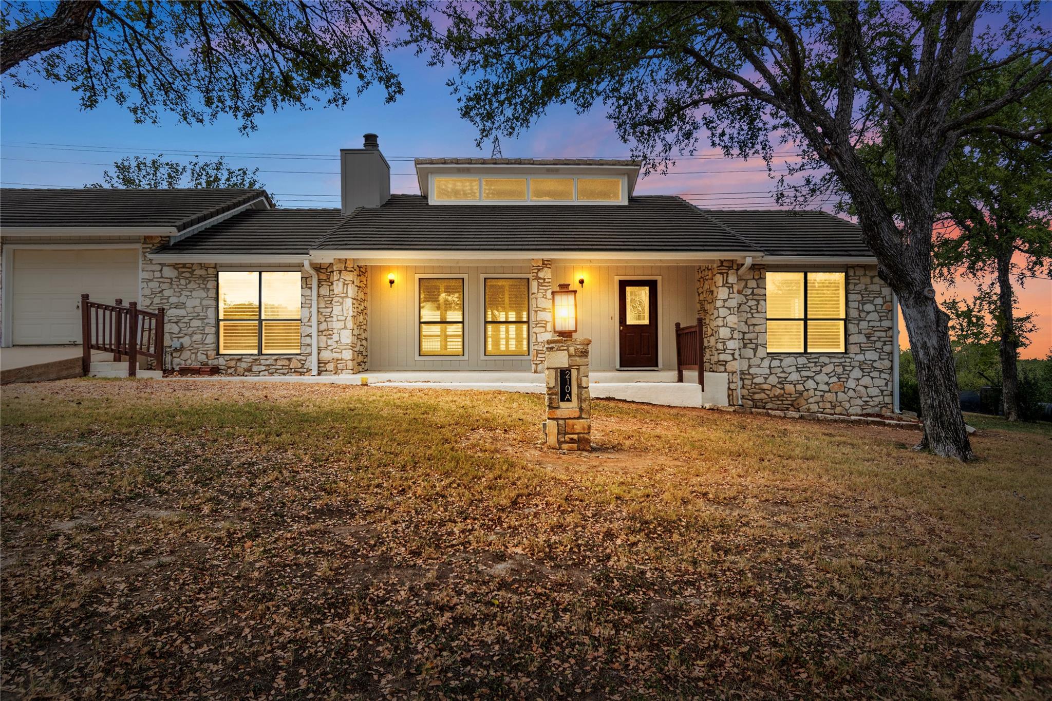 Natural stone accents and mature trees frame this