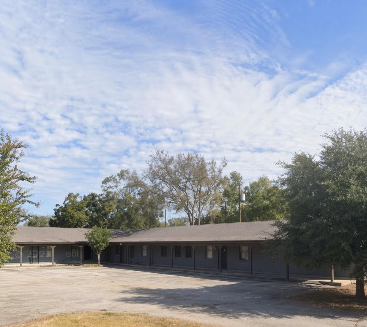 A spacious paved parking area fronts this low-pro