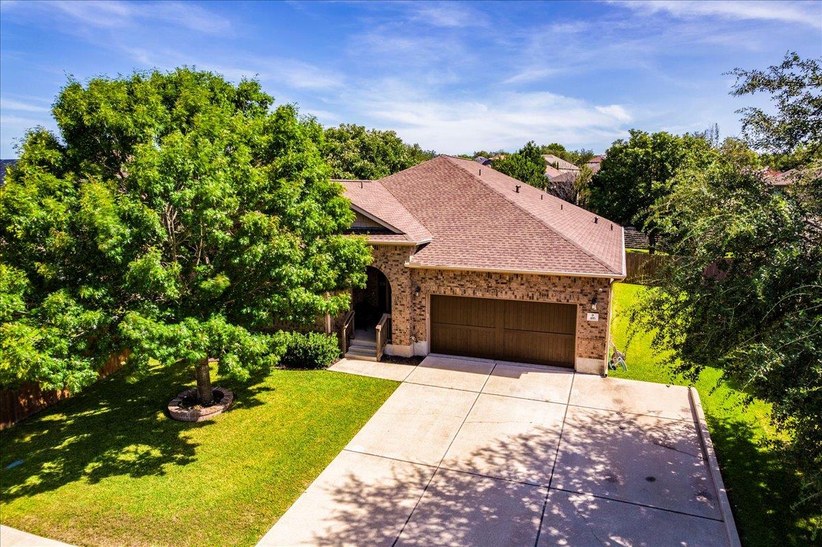 Mature trees shade a wide concrete driveway leadi