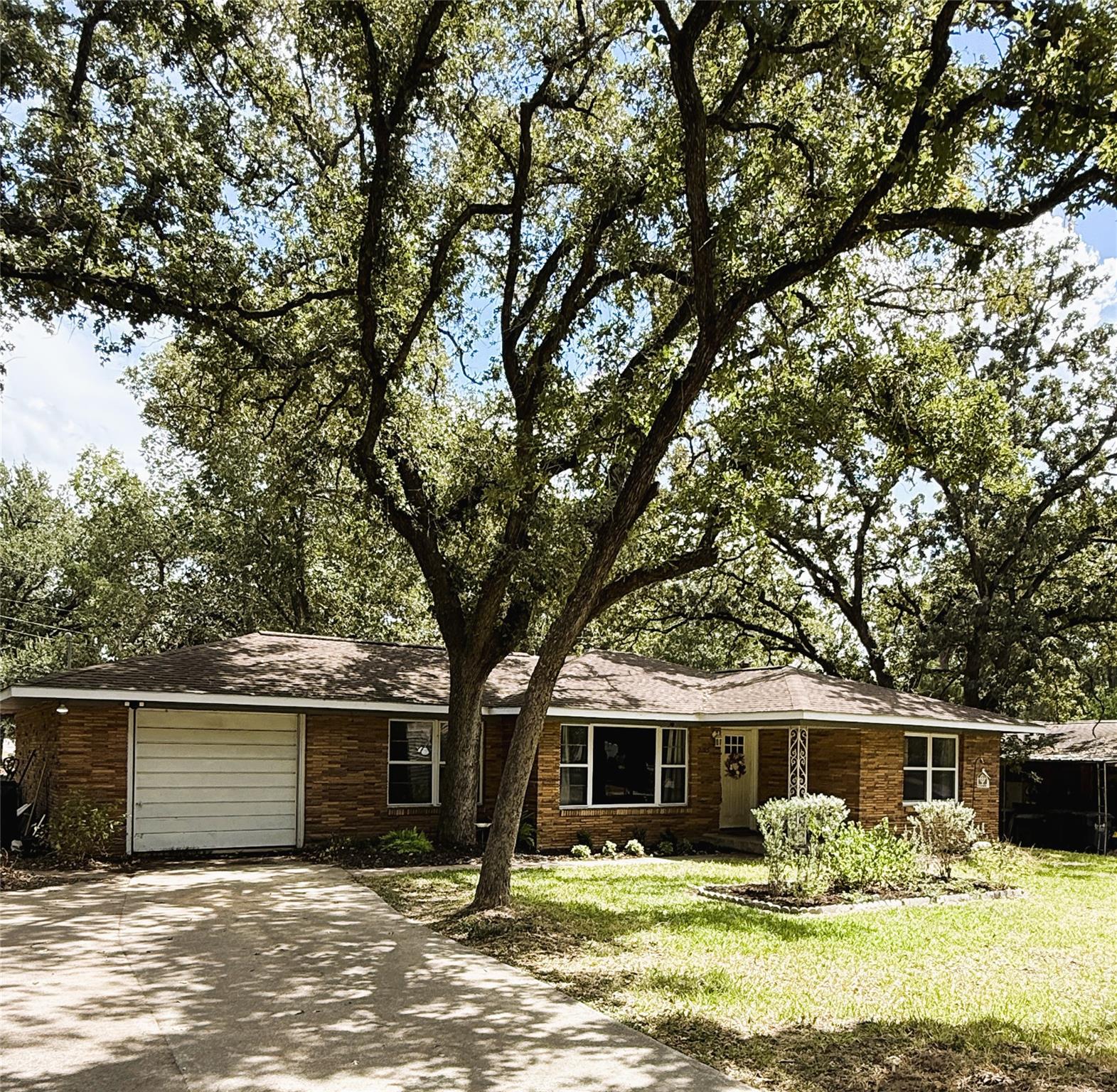 Mature shade trees frame this classic brick singl