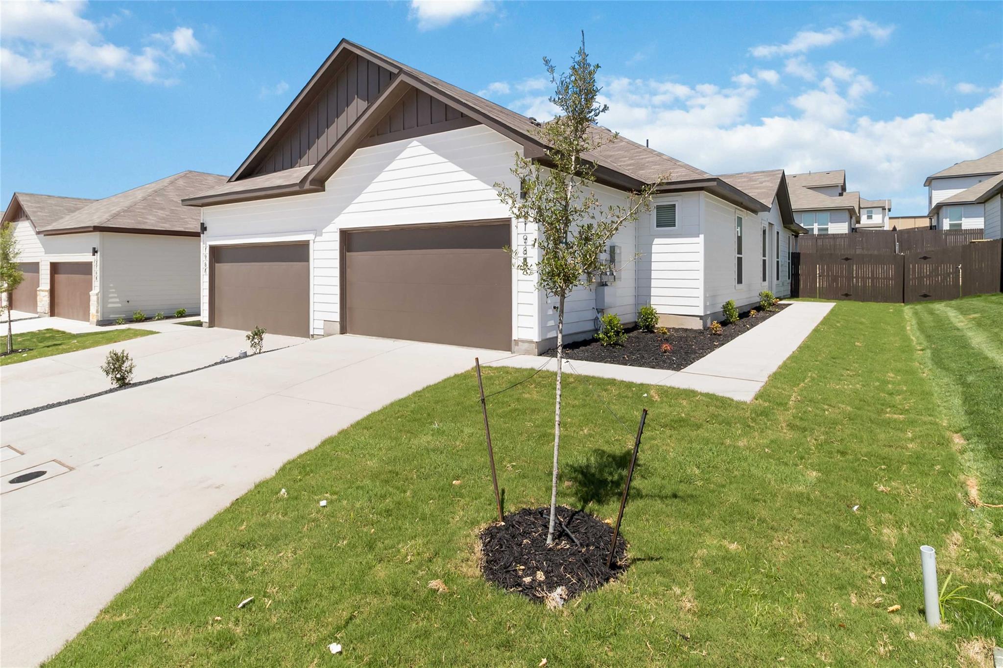 Crisp white siding and a neat concrete driveway e