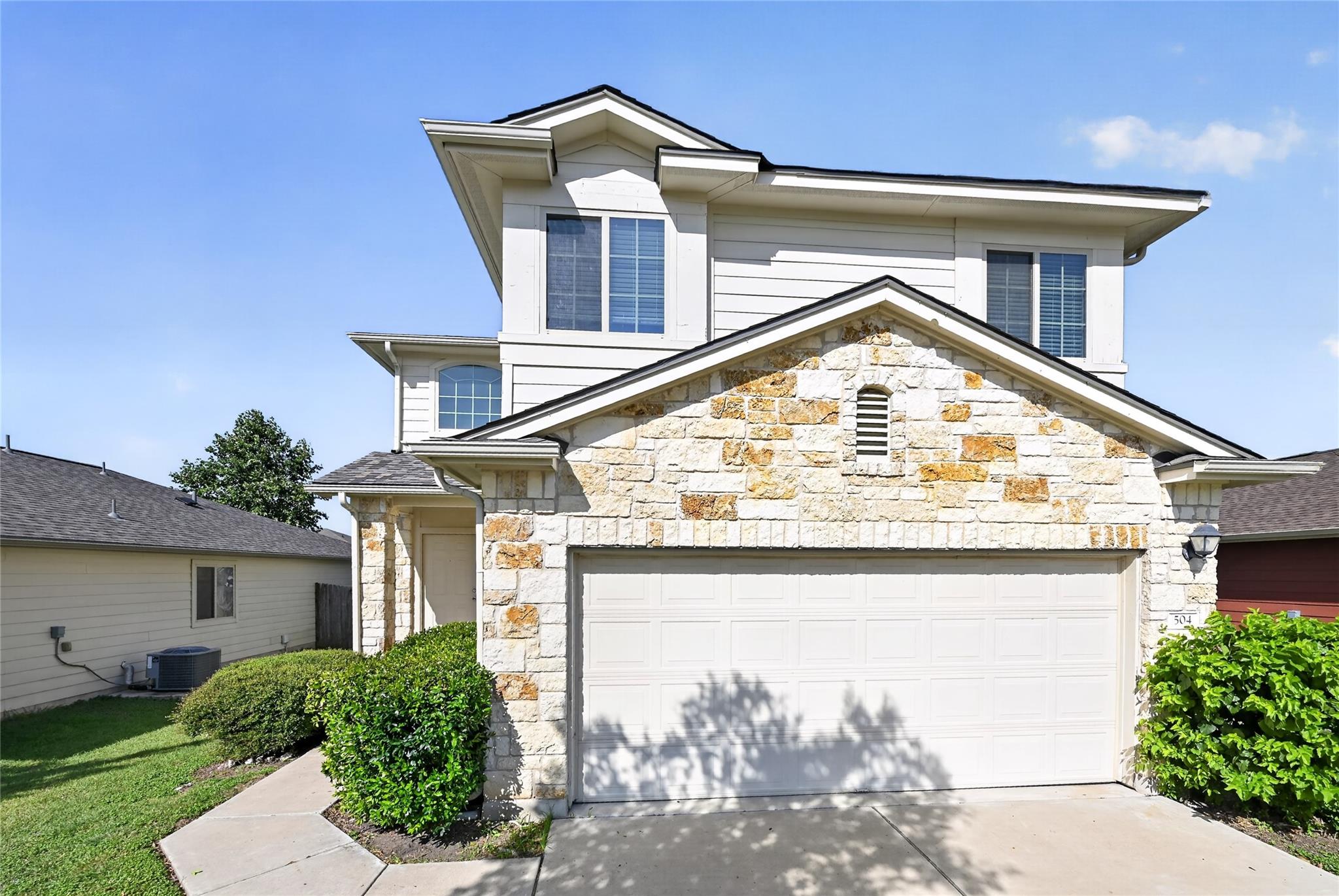 Natural stone accents and a wide driveway create 