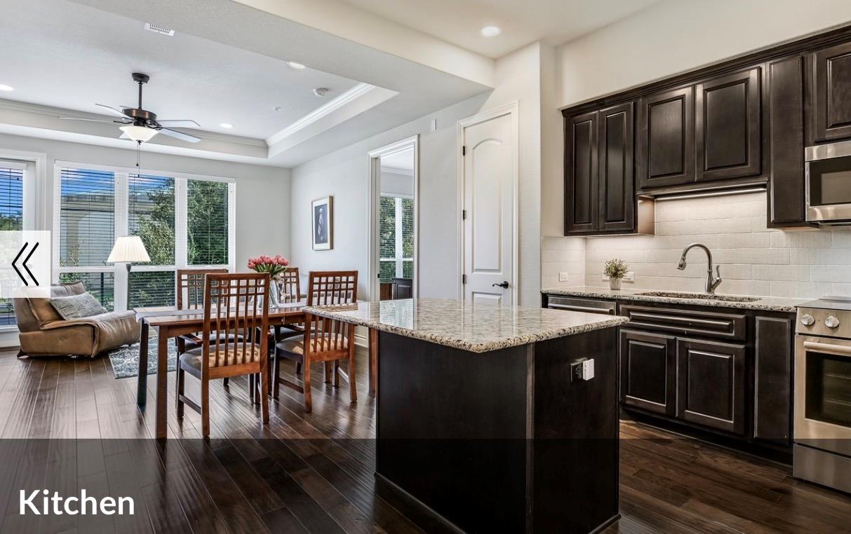 Rich dark cabinetry and a polished stone island a