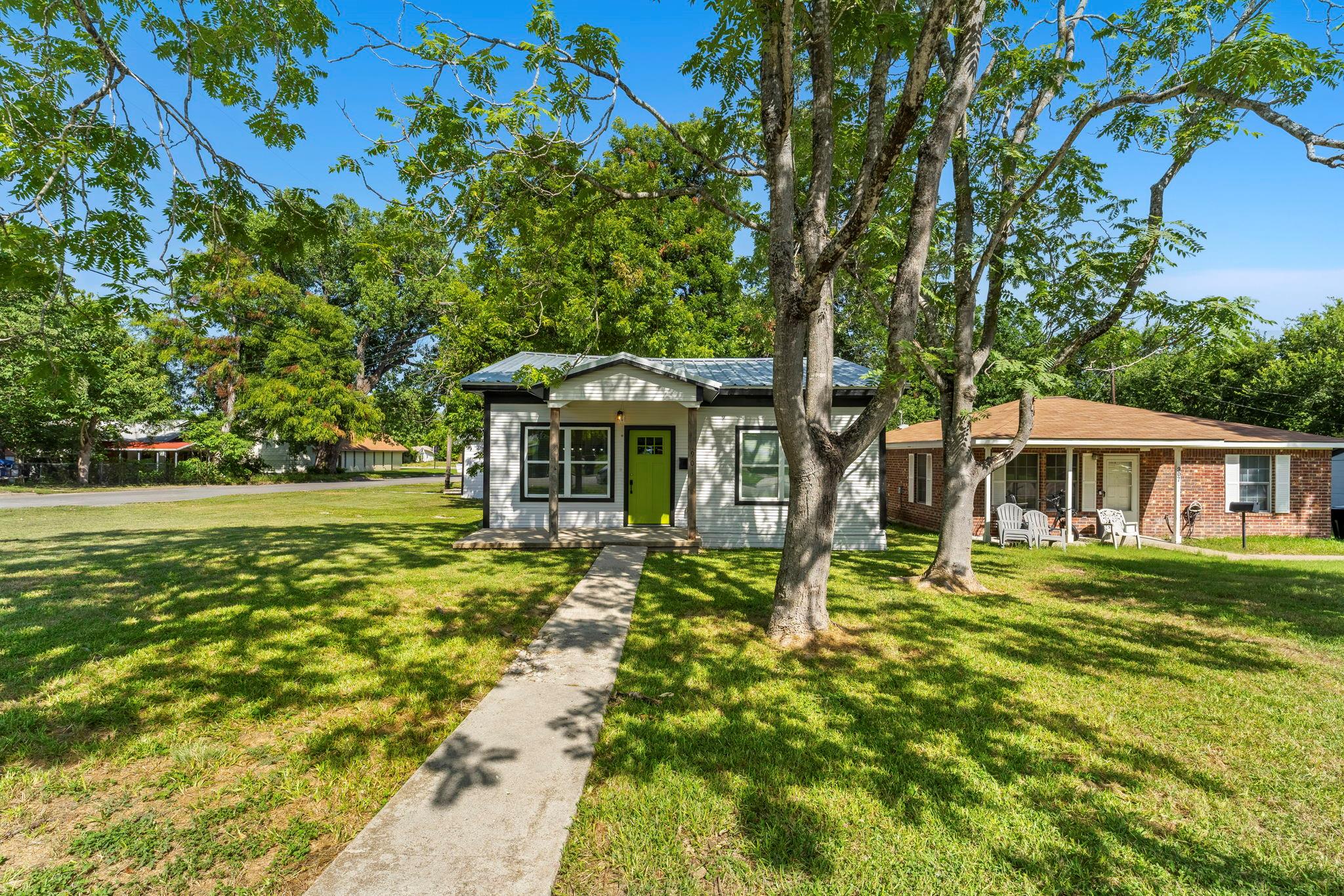 Mature trees shade the concrete walkway leading t