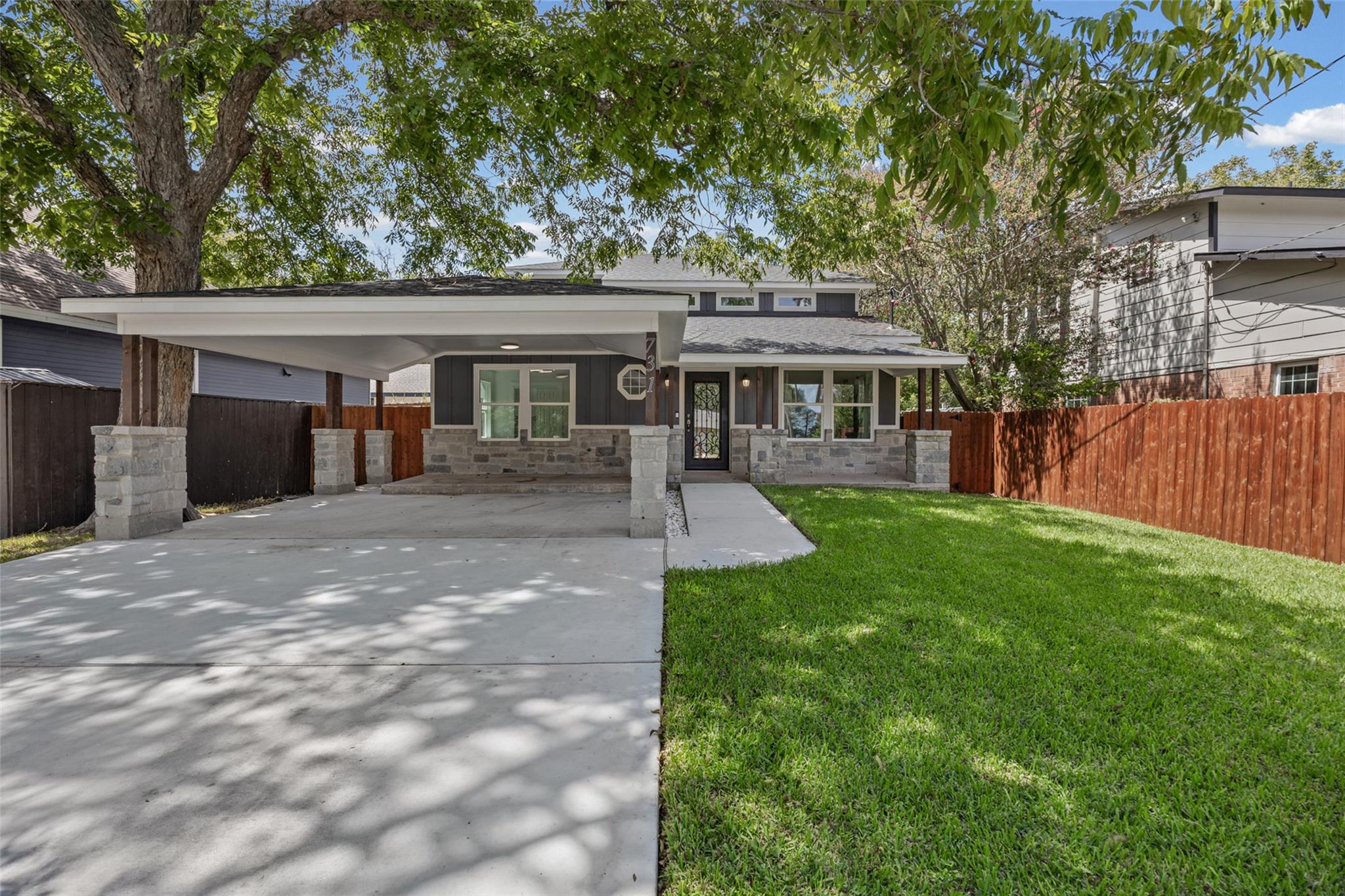 Mature trees shade a neat front lawn and a spacio