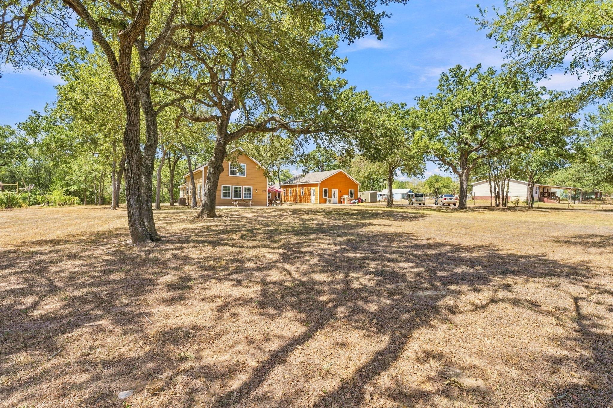Mature oak trees cast cooling shade across an exp