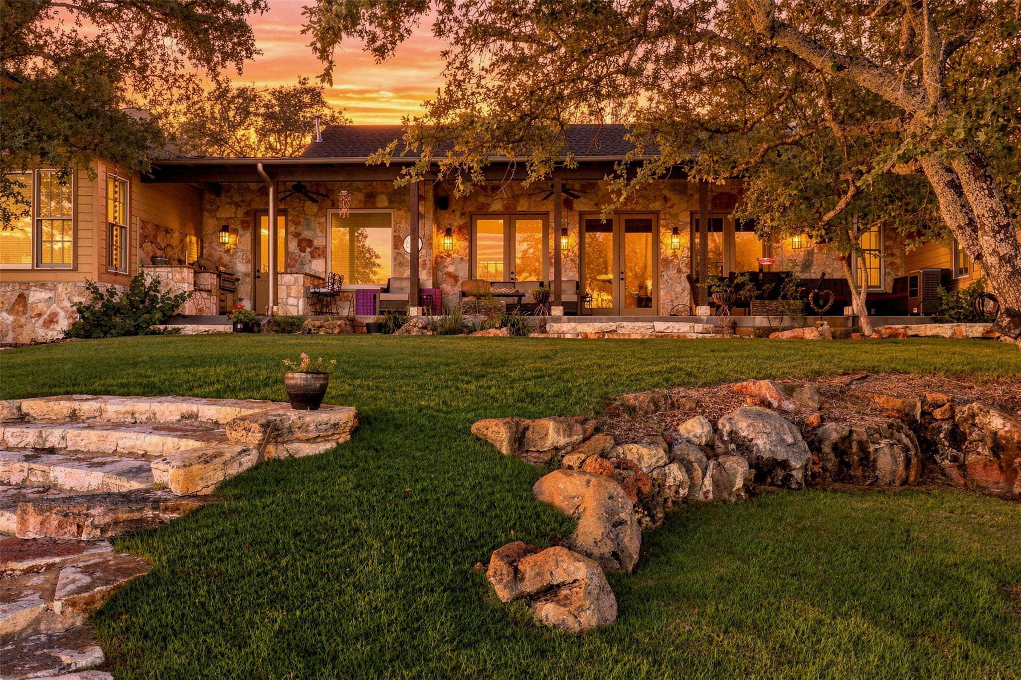 Mature oak trees frame a stone-accented exterior 