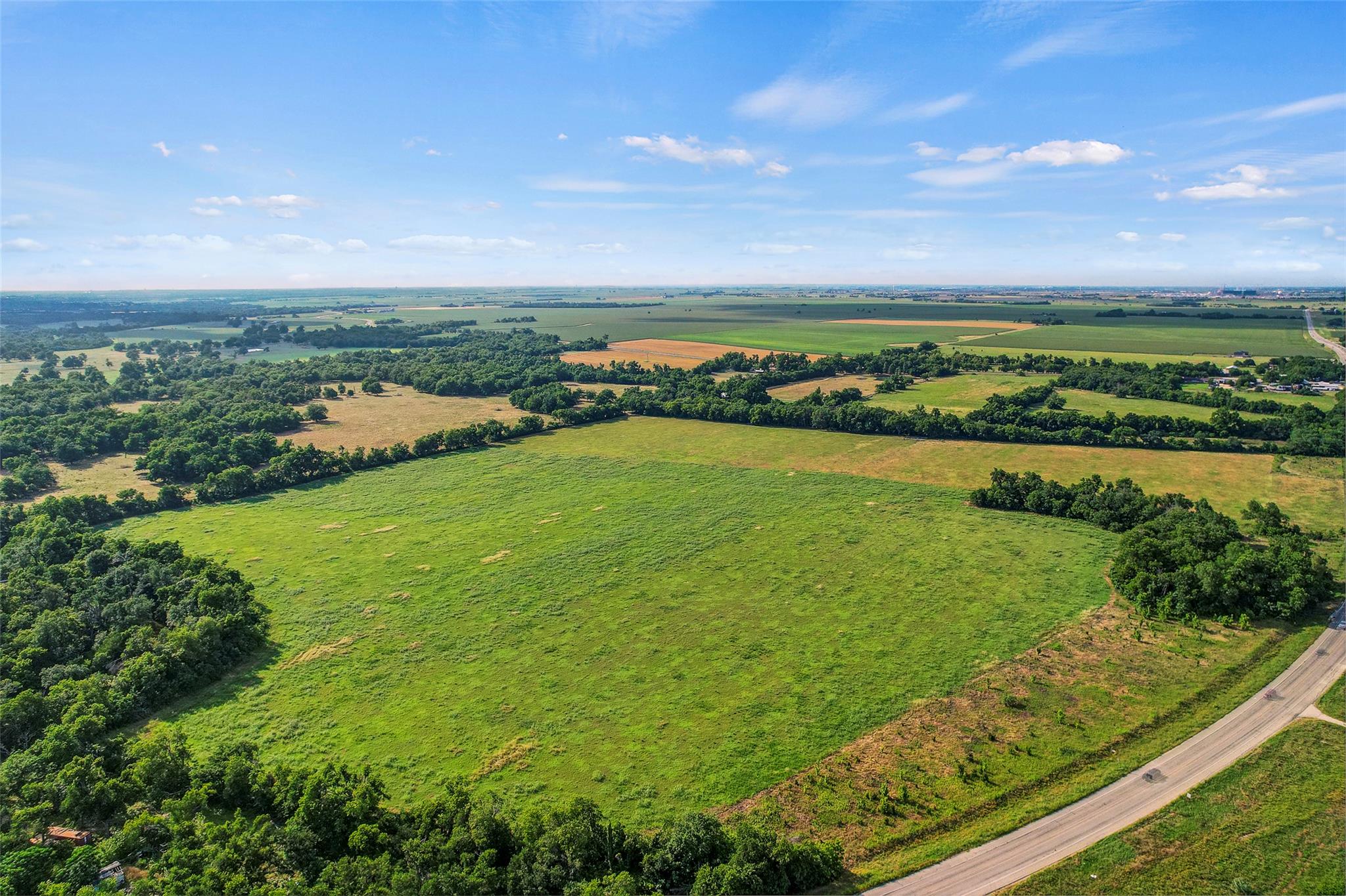 Vast green pastures and dense treelines stretch t