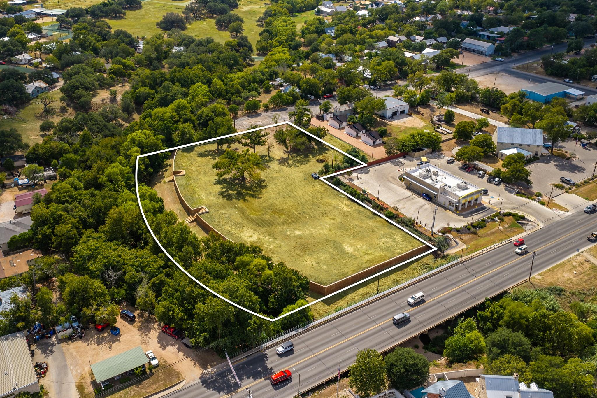 Mature trees frame this expansive cleared lot bor