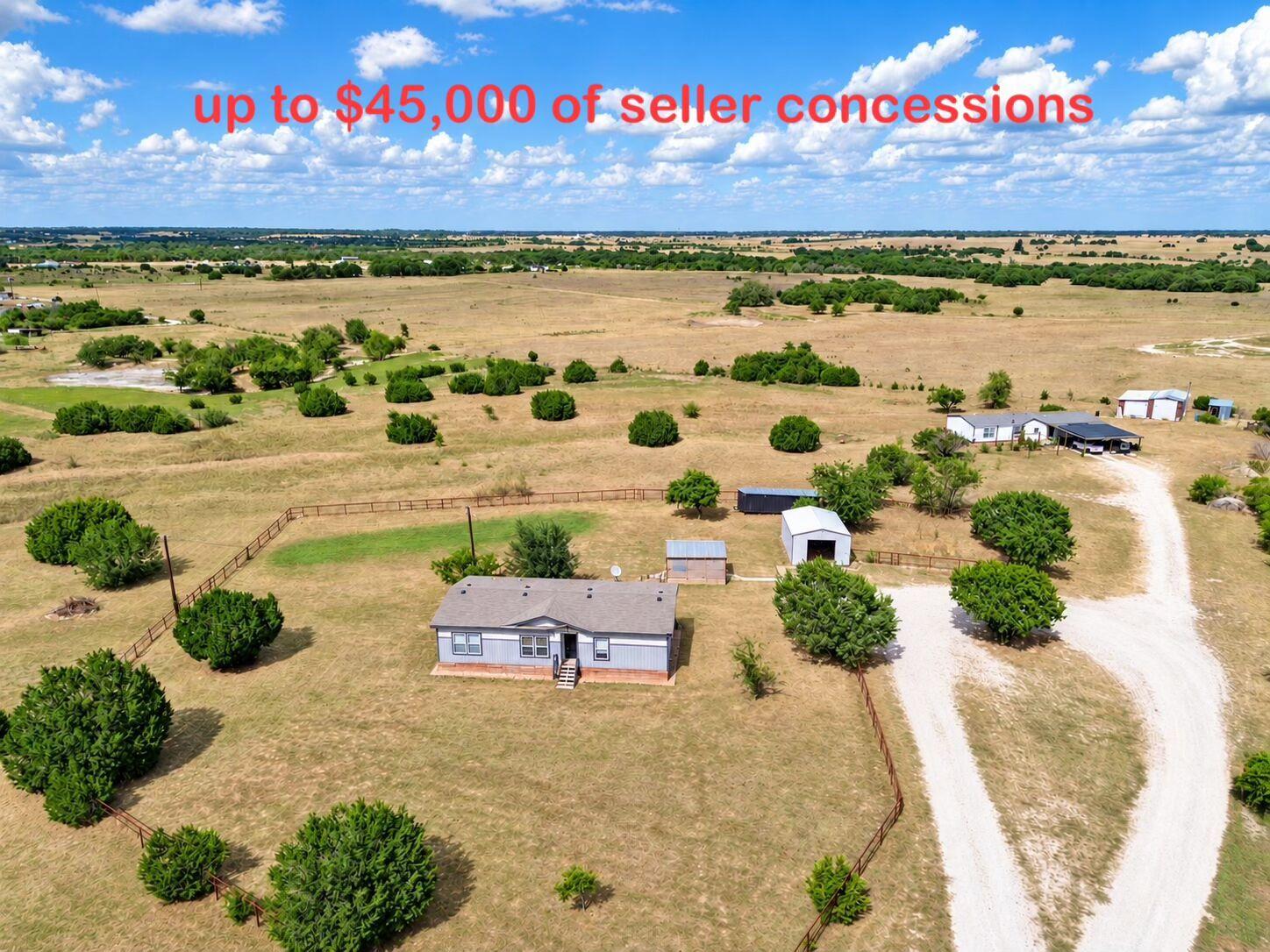 A gravel driveway winds past outbuildings on this