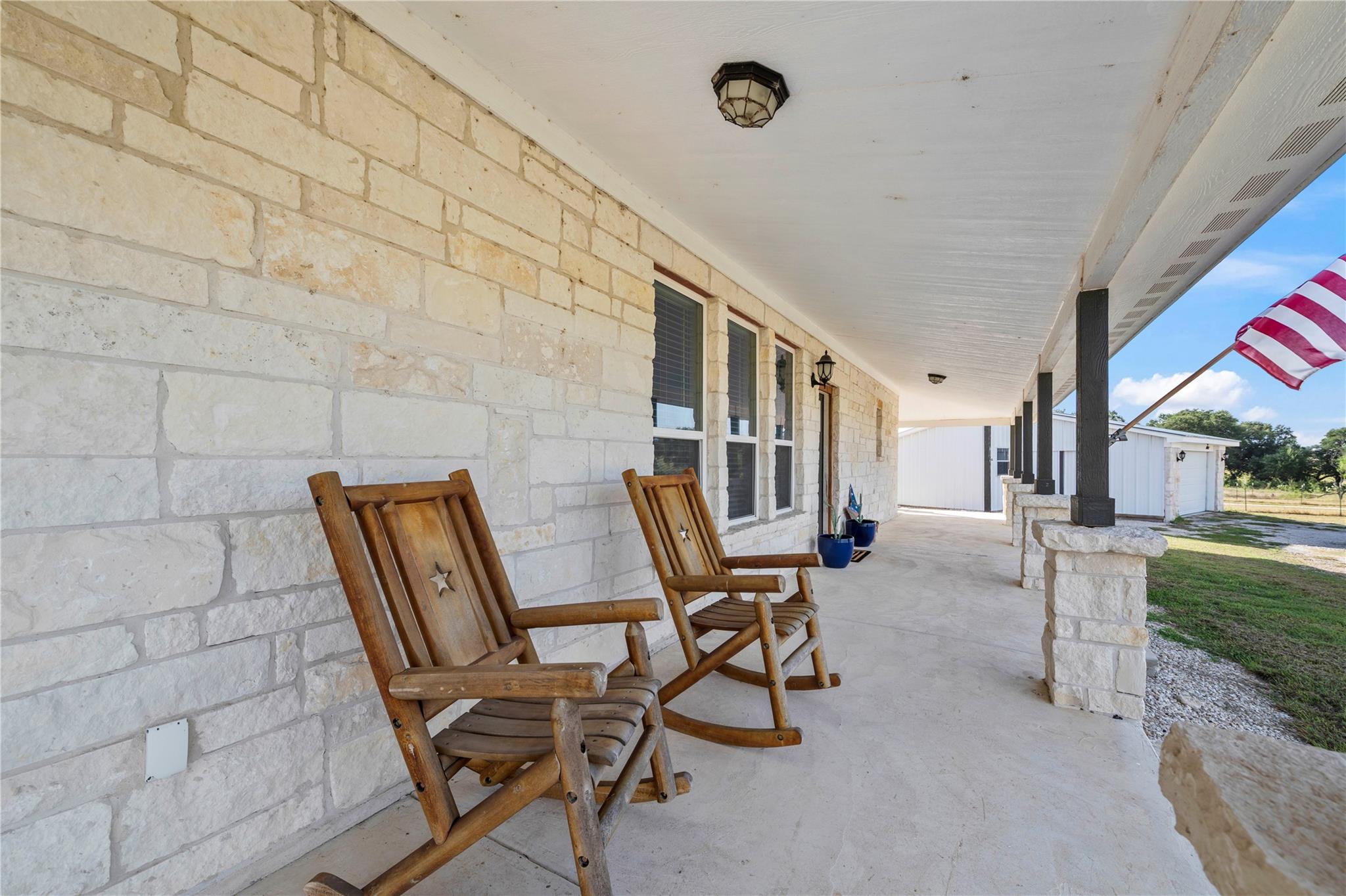An inviting covered porch features solid stone ma