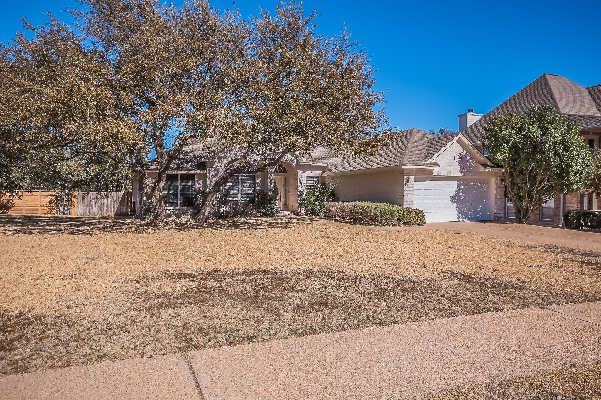 Mature trees shade a classic brick facade with an
