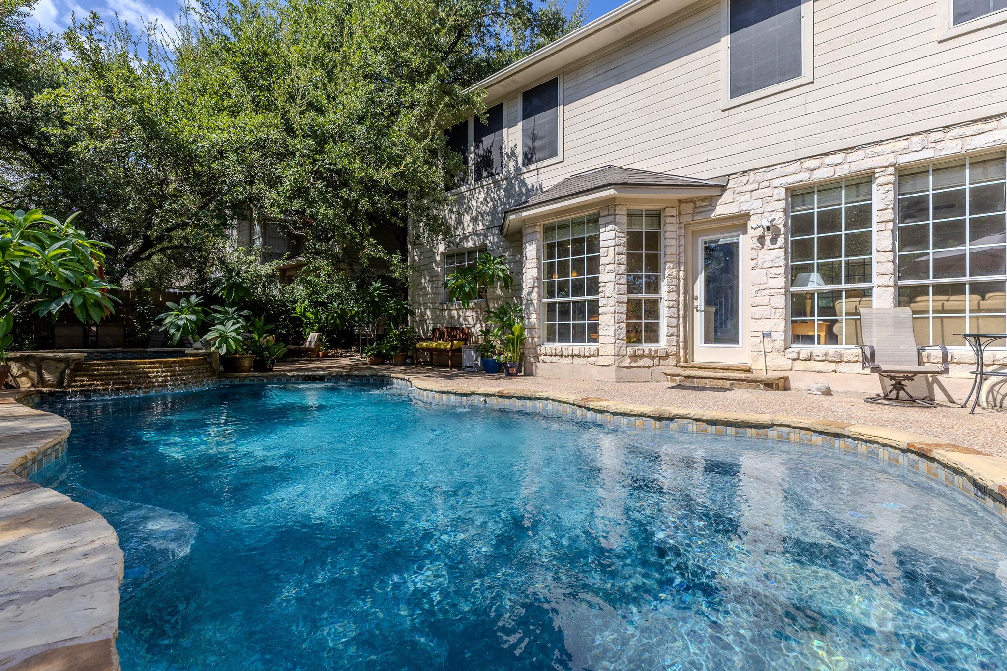 Mature trees frame a private backyard swimming po