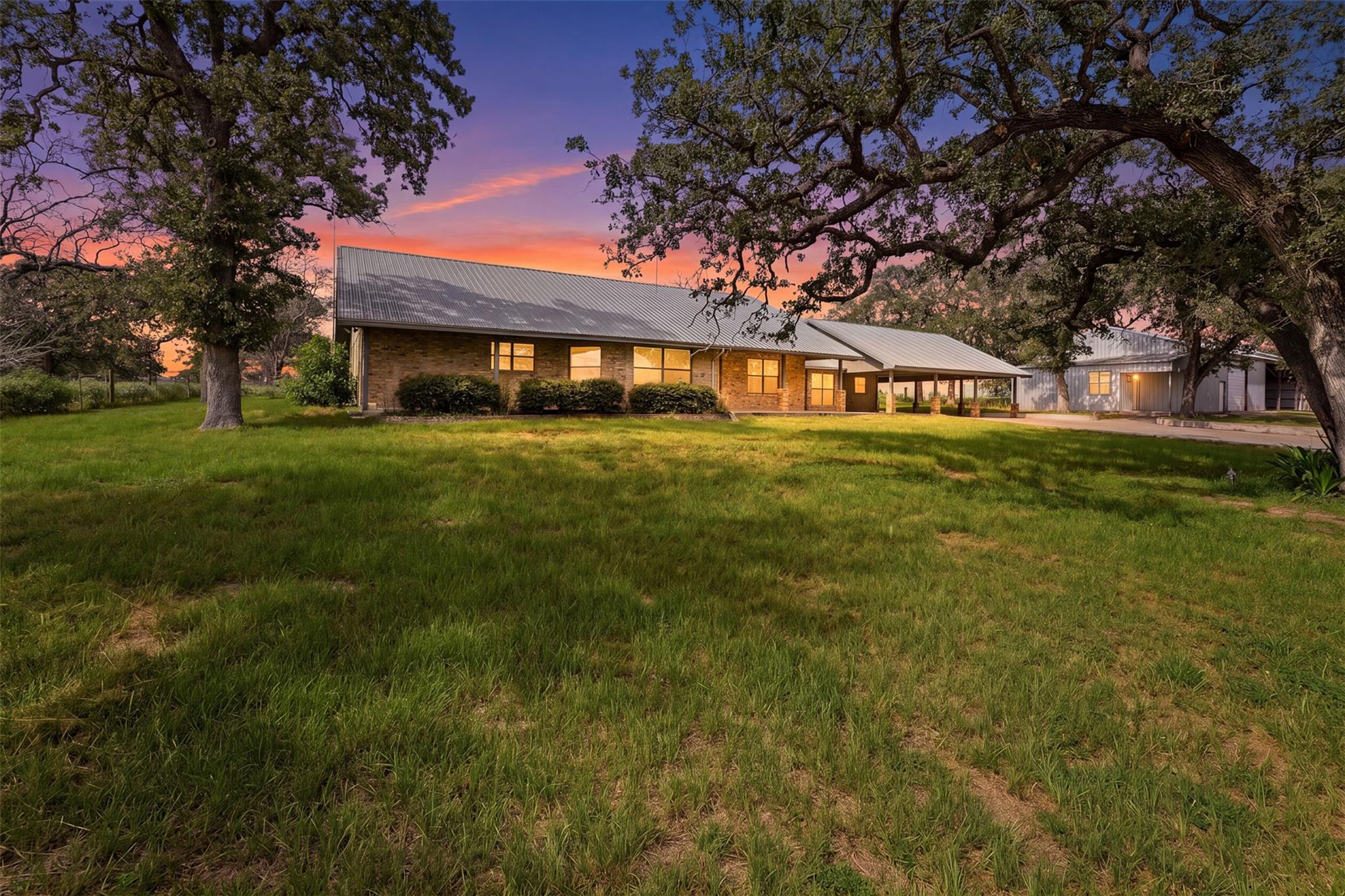 Mature oak trees frame this classic brick ranch-s