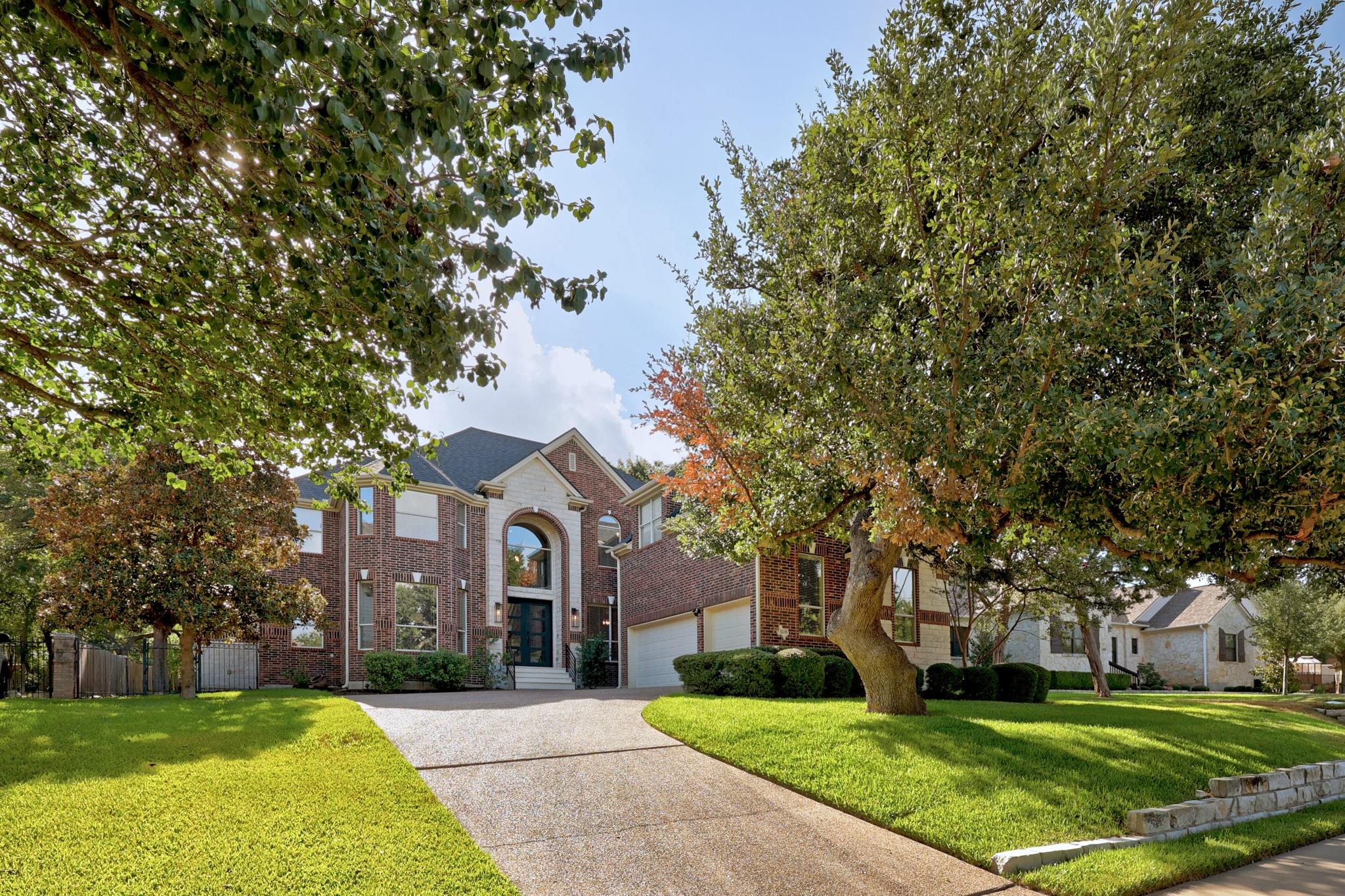 Mature trees frame a welcoming concrete driveway 