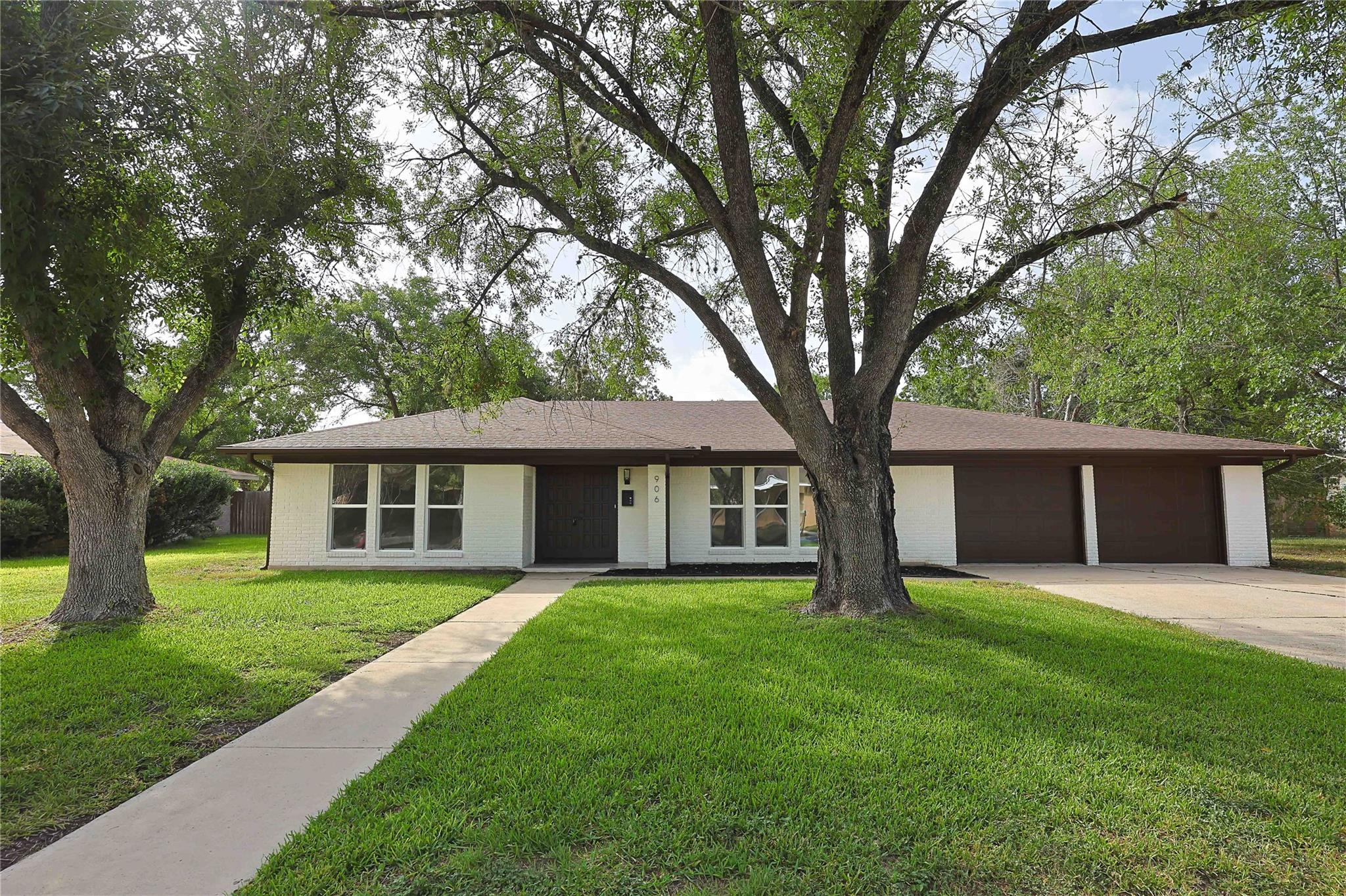 Mature trees shade a welcoming paved walkway lead