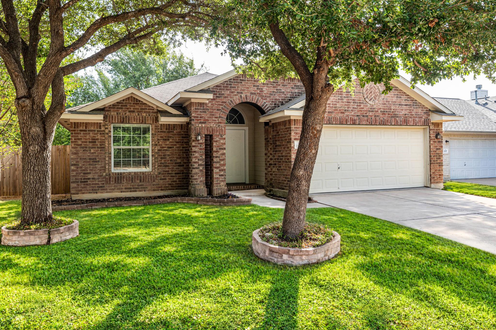 Mature shade trees frame a classic brick facade w