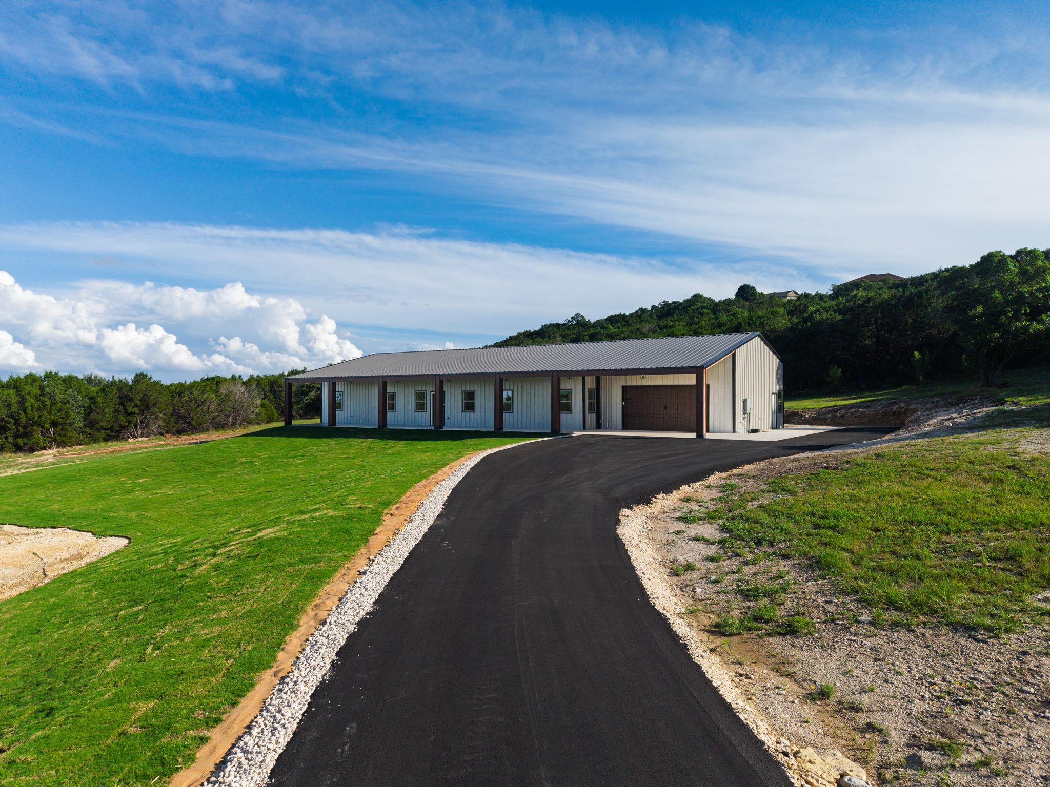 A long paved driveway leads up to this modern met