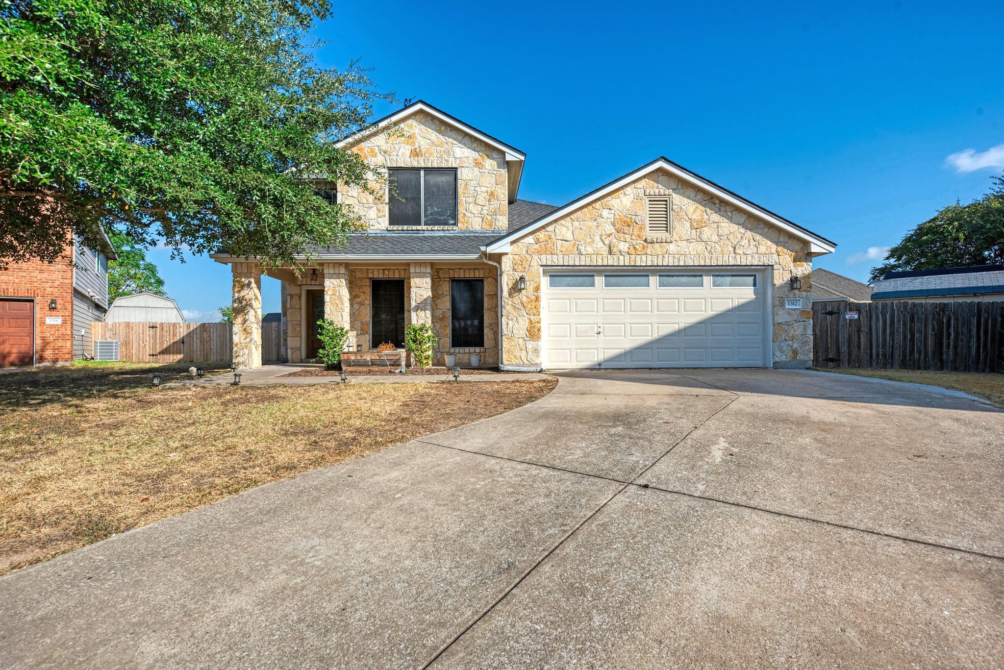 A spacious concrete driveway leads to this two-st