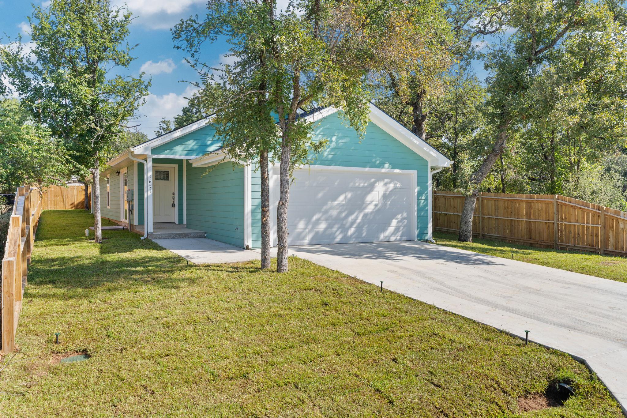 Mature trees shade the concrete driveway and neat
