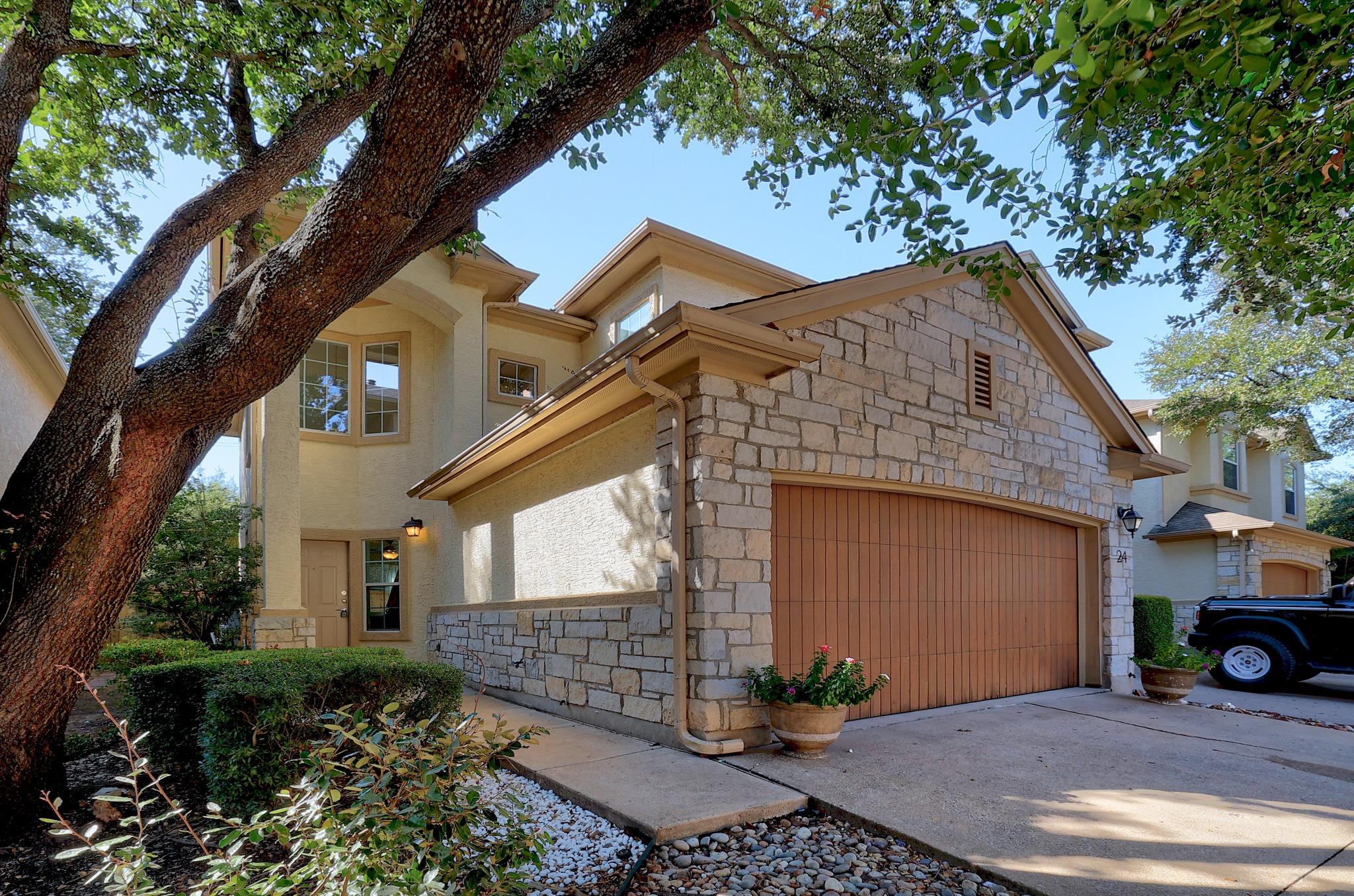 Mature shade trees frame a multi-level stone and 