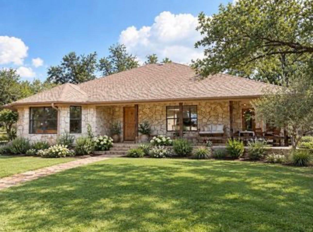 Mature trees shade a manicured lawn leading to th