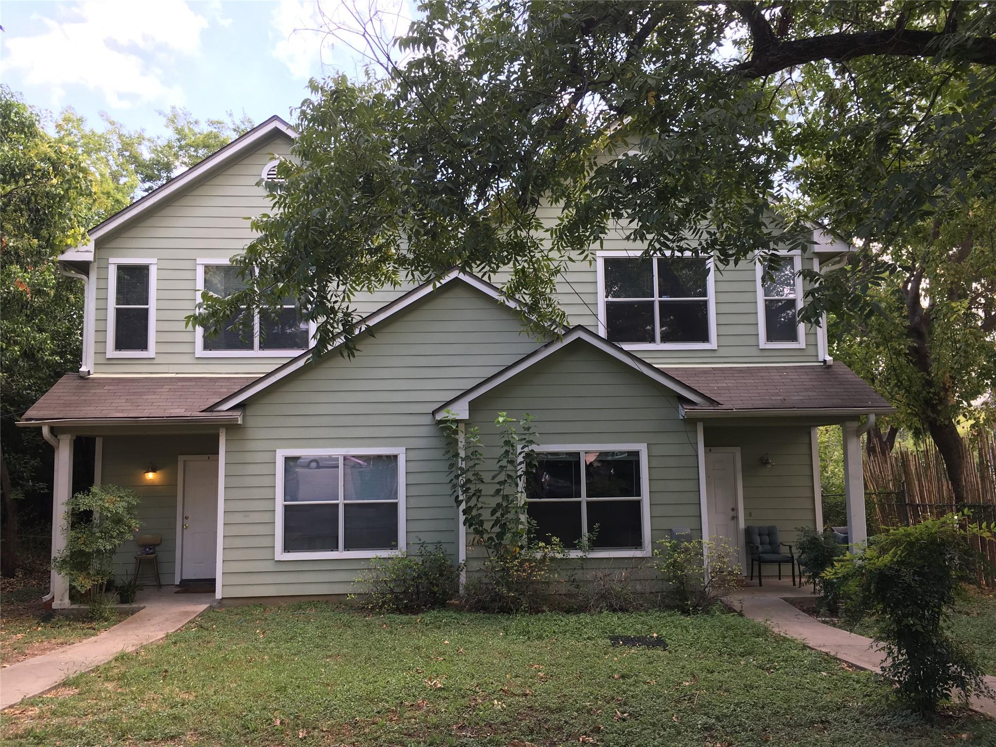 Mature trees frame a classic duplex exterior feat